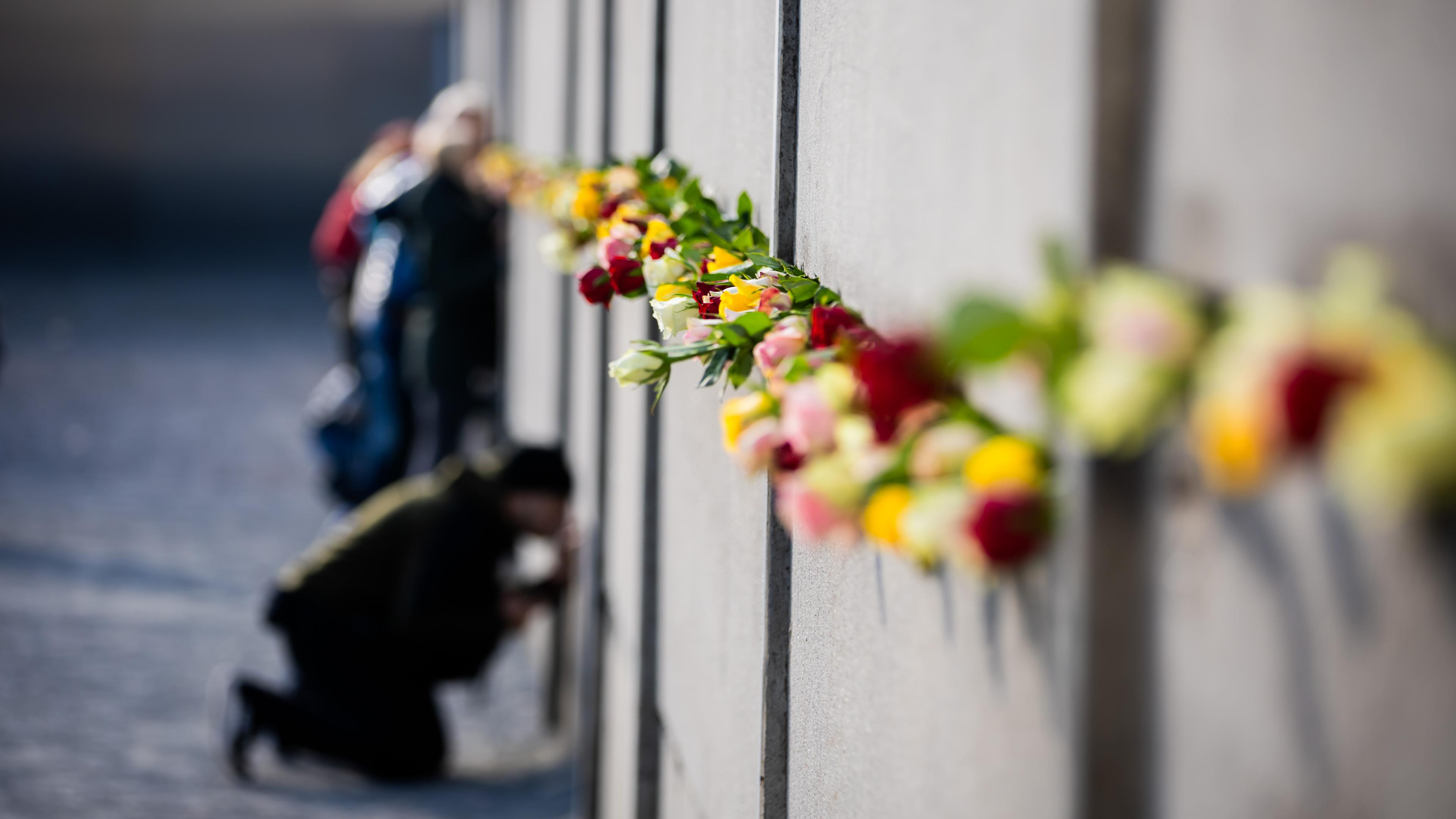 35 Jahre Mauerfall - Zentrale Gedenkveranstaltung - Menschen stecken Blumen in die Reste der Mauerdpa/ 