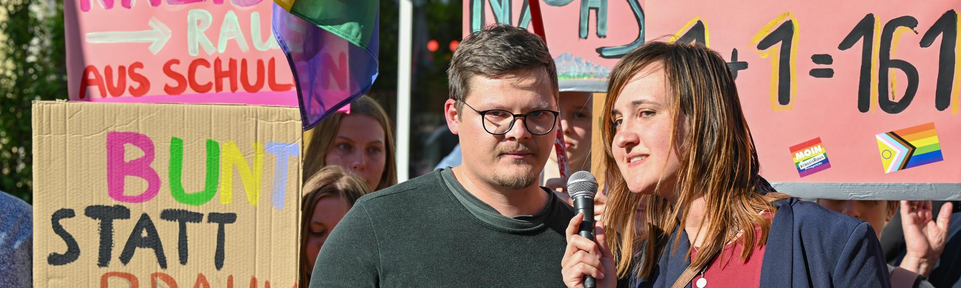 Der Lehrer Max Teske und seine Kollegin Laura Nickel bei einer Kundgebung. Im Hintergrund Plakate.