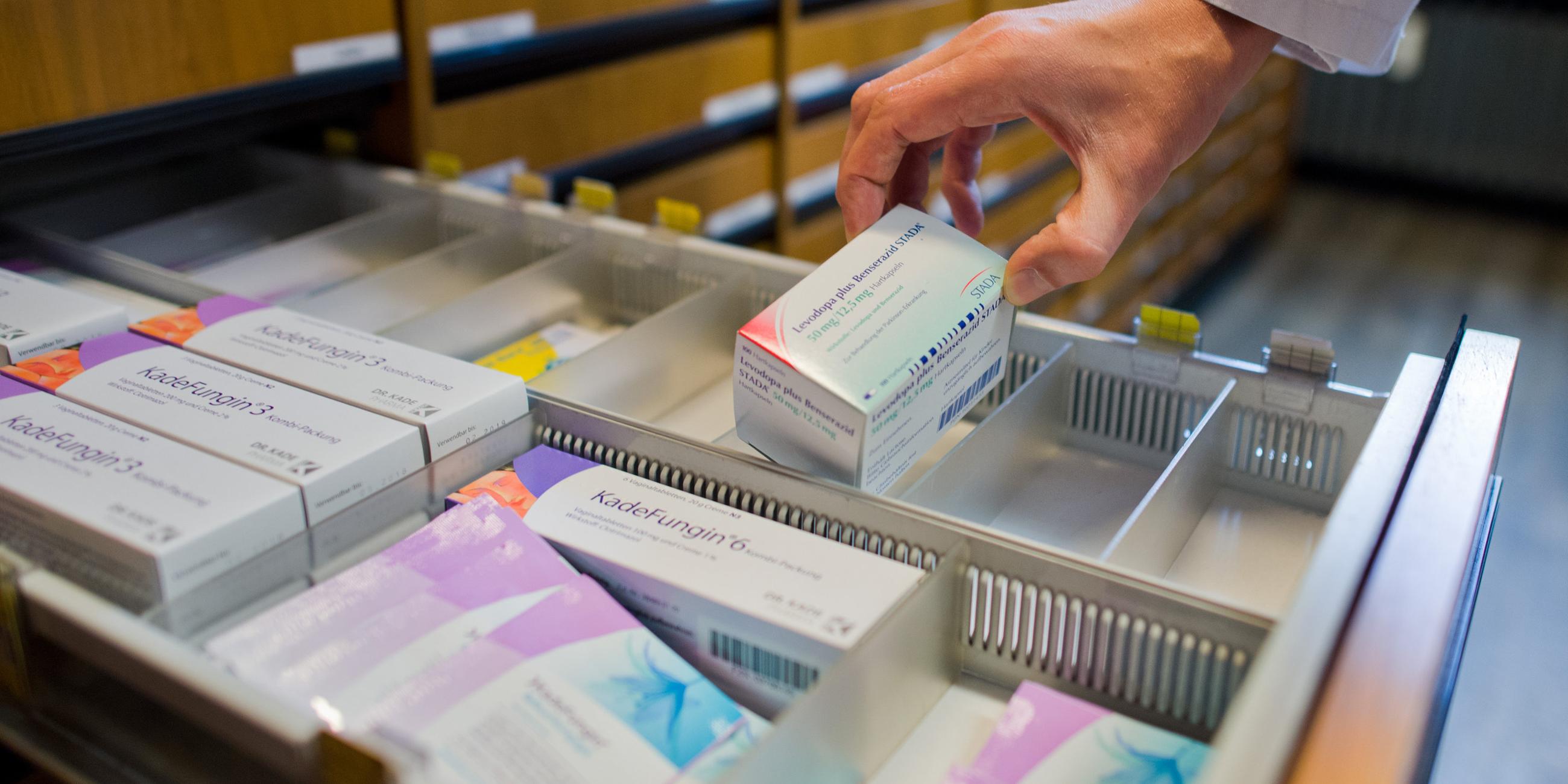 Apotheker nimmt Medikamente aus einer Schublade