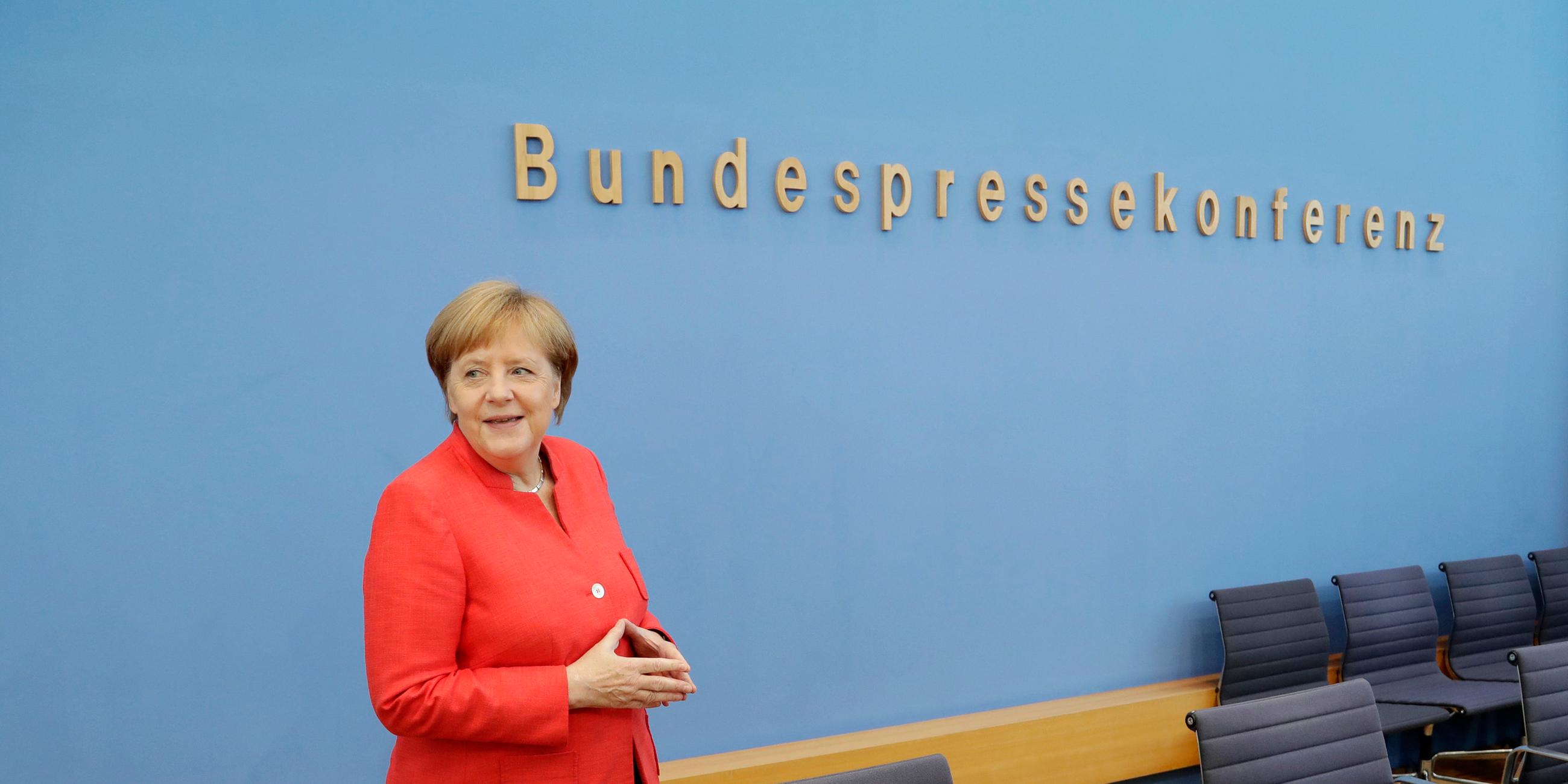 Angela Merkel vor dem Schriftzug der Budnespressekonferenz. Lächelnd, die Hände zur Raute geformt. Aufgenommen am 20.07.2018