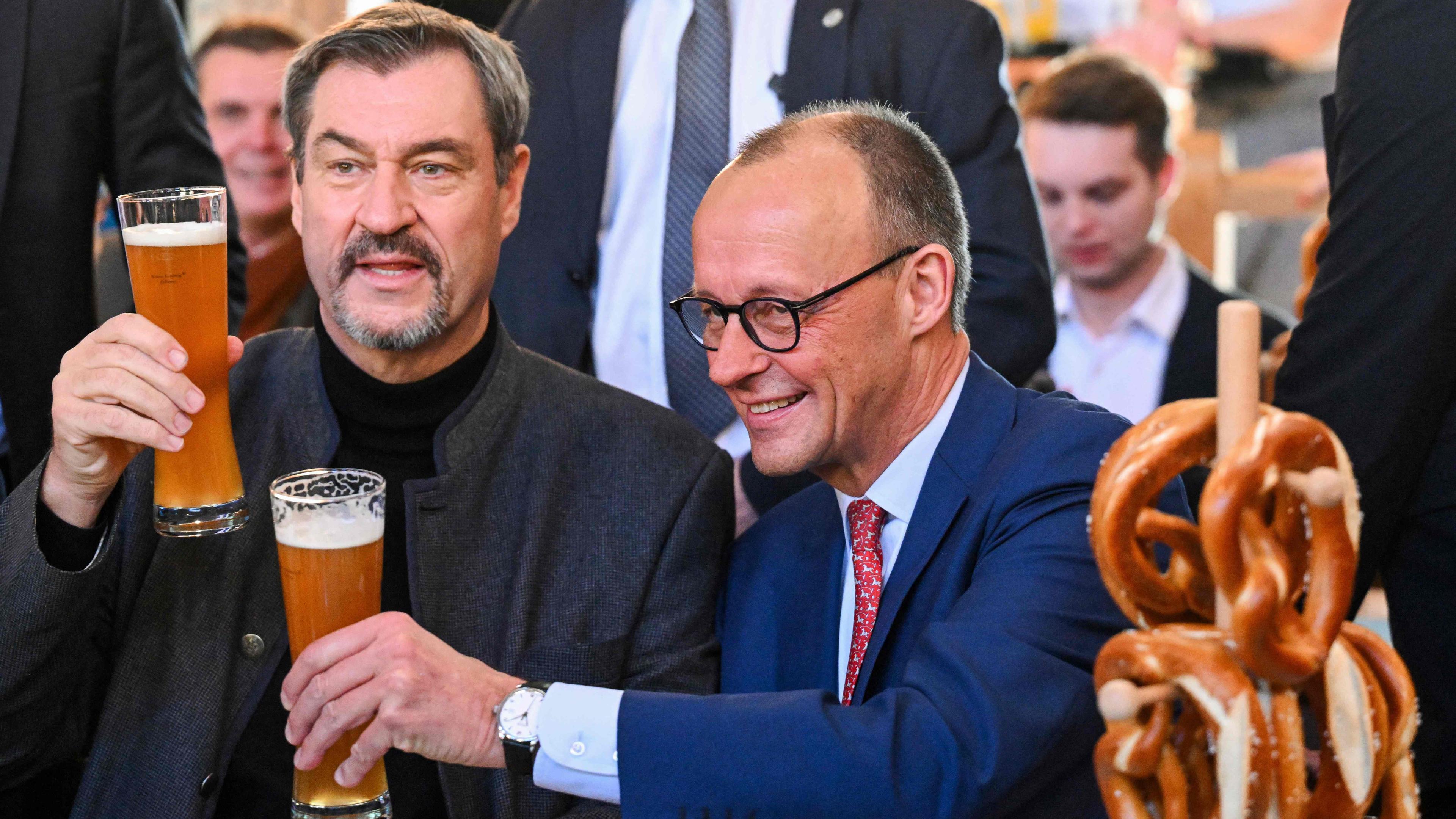 Der CDU-Vorsitzende Merz und CSU-Chef Söder trinken während einer Wahlkampfveranstaltung ein Bier.