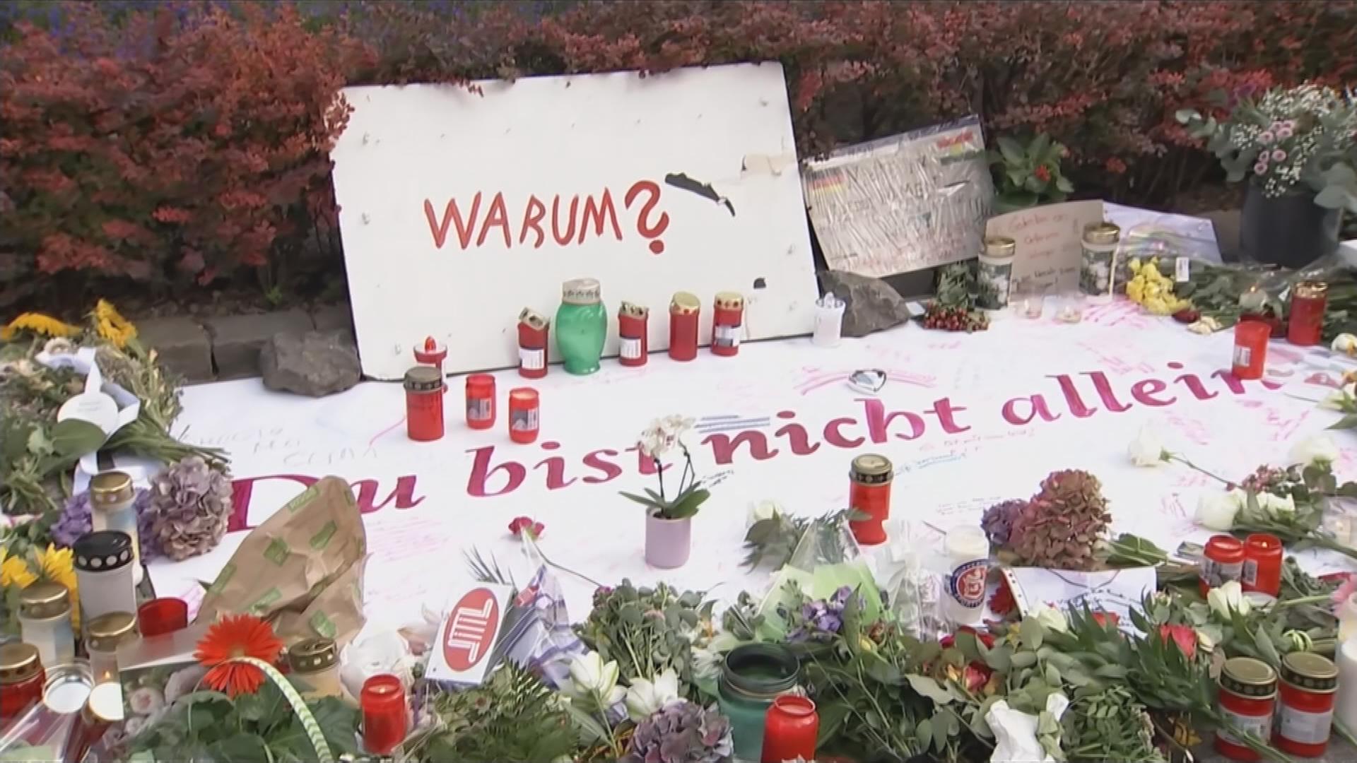 Kerzen und Kränze mit Schild "Warum? Du bist nicht allein."