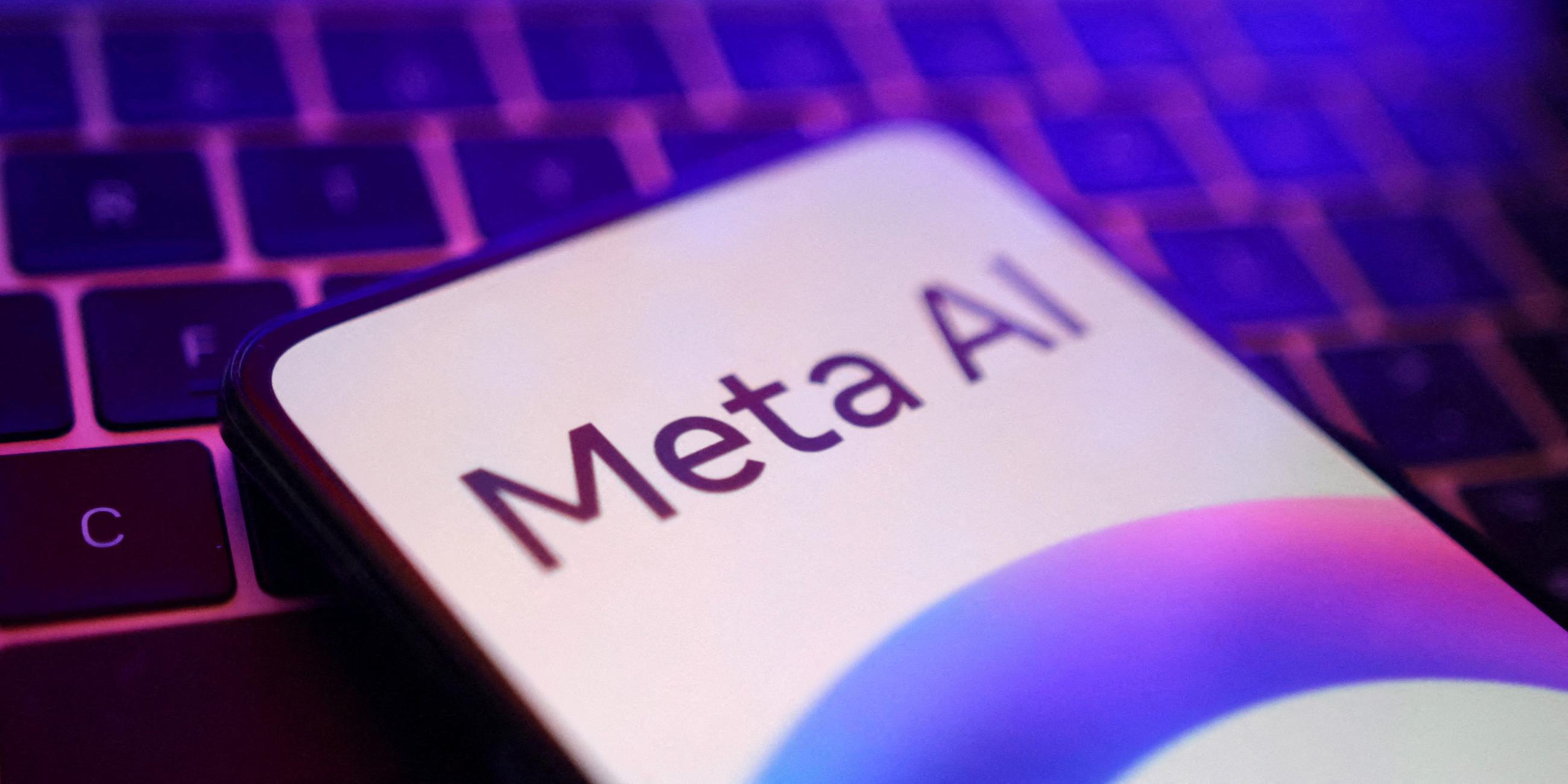 Ein Smartphone liegt auf einer Computertastatur, auf dem Smartphonebildschirm wird "Meta AI" angezeigt.