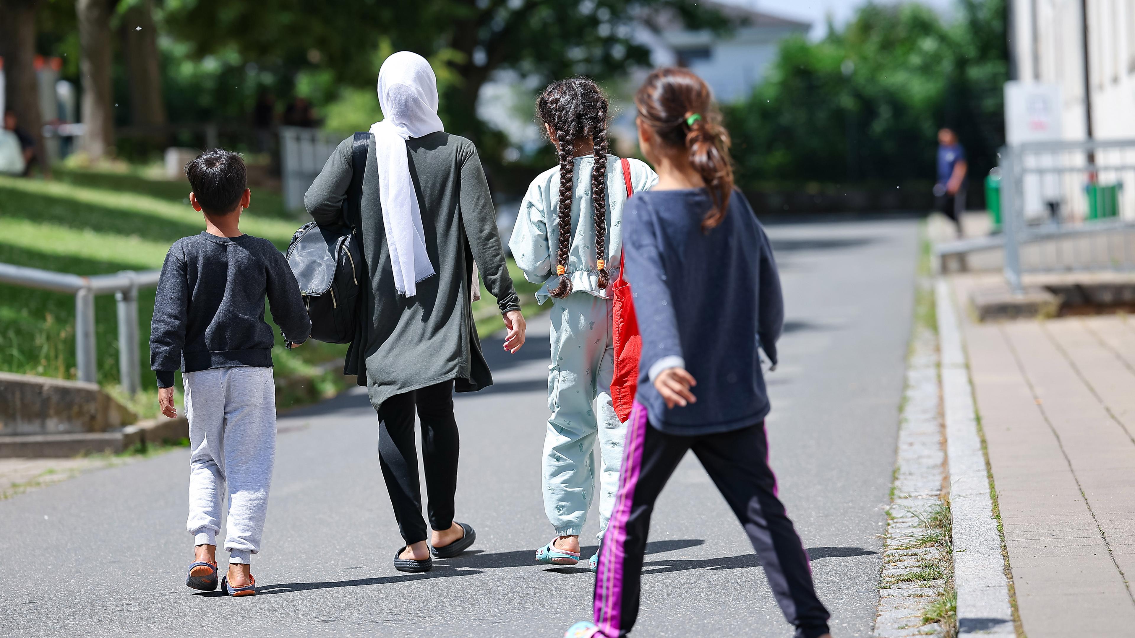 Bayern, Zirndorf: Eine Familie Flüchtlinge und Migranten gehen in der Zentralen Aufnahmeeinrichtung für Asylbewerber in Bayern über das Gelände.