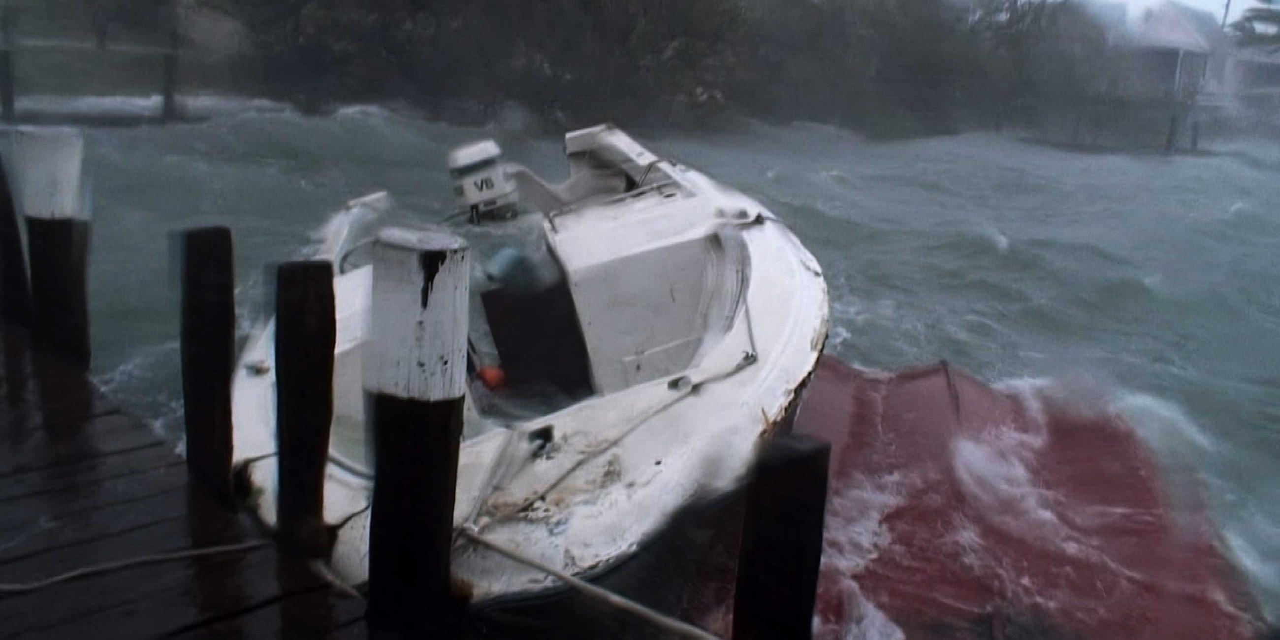 An einer Mole ist ein Motorboot angebunden. Es gibt starken Wellengang, und das Boot schwankt zur Seite.