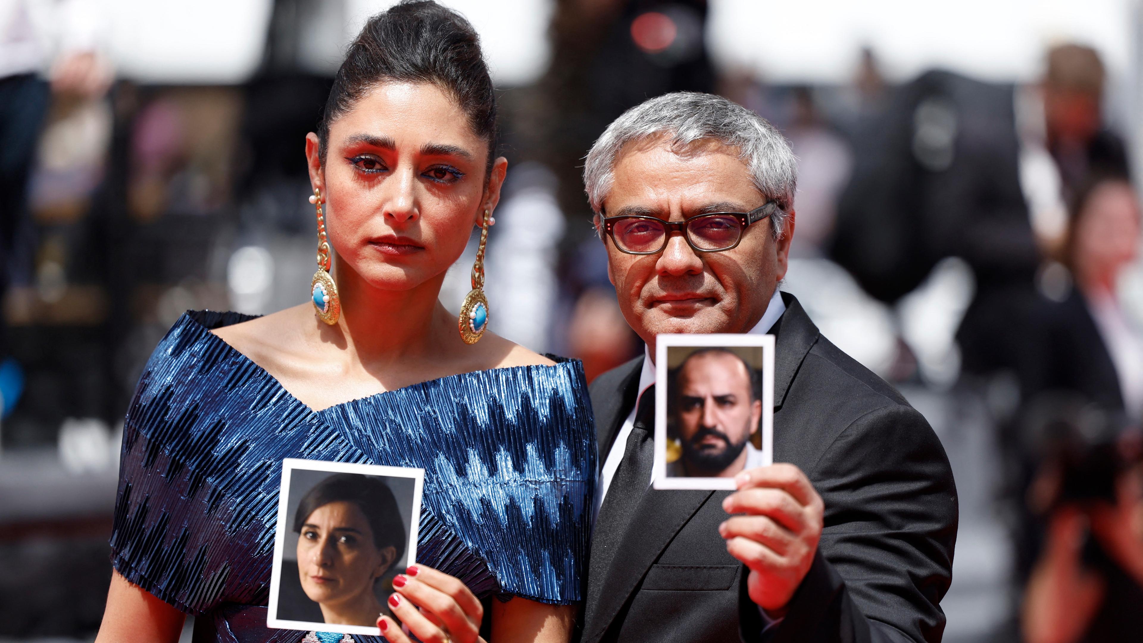 Mohammad Rasoulof und Golshifteh Farahani stehen auf dem roten Teppich und halten Bilder der Schauspieler Missagh Zareh und Soheila Golestani hoch