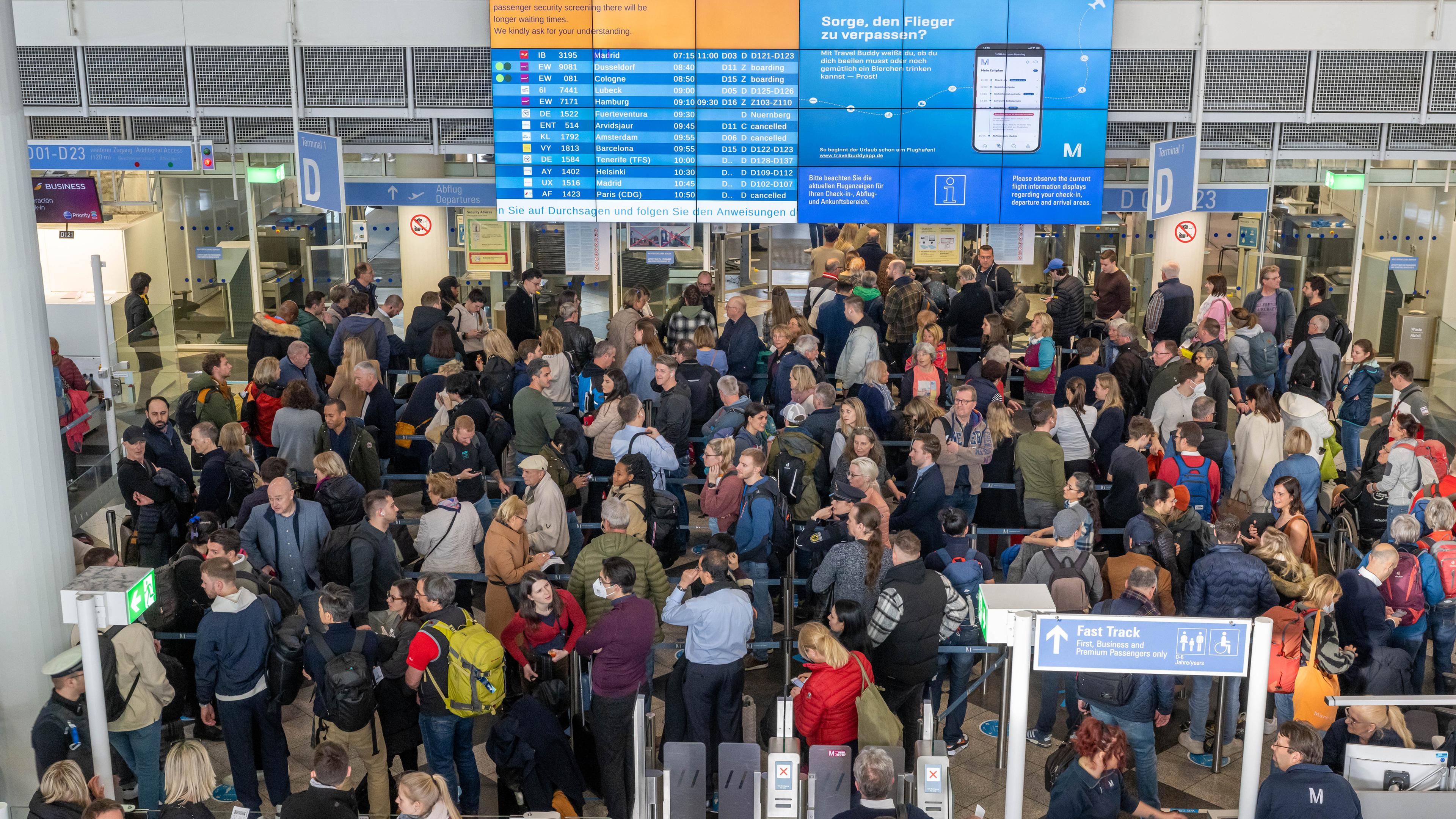 Bayern, München-Flughafen: Passagiere stehen in der Abflughalle in Schlangen an, um zur Sicherheitskontrolle zu gelangen. 