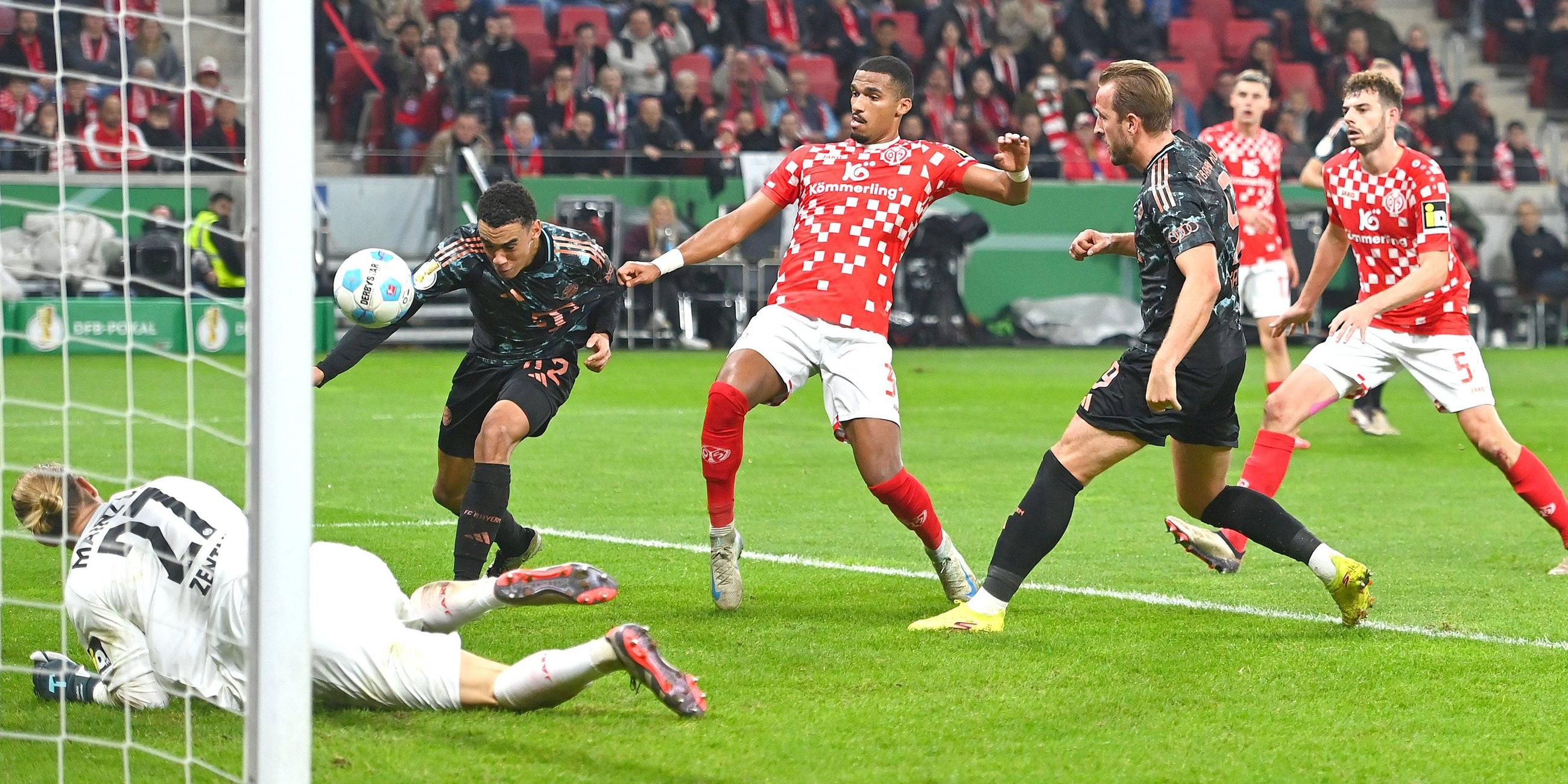 Jamal Musiala erzielt mit einem Kopfball das 2:0 für den FC Bayern beim FSV Mainz 05. Torwart Robin Zentner ist geschlagen. Moritz Jenz kommt zu spät, rechts Harry Kane.