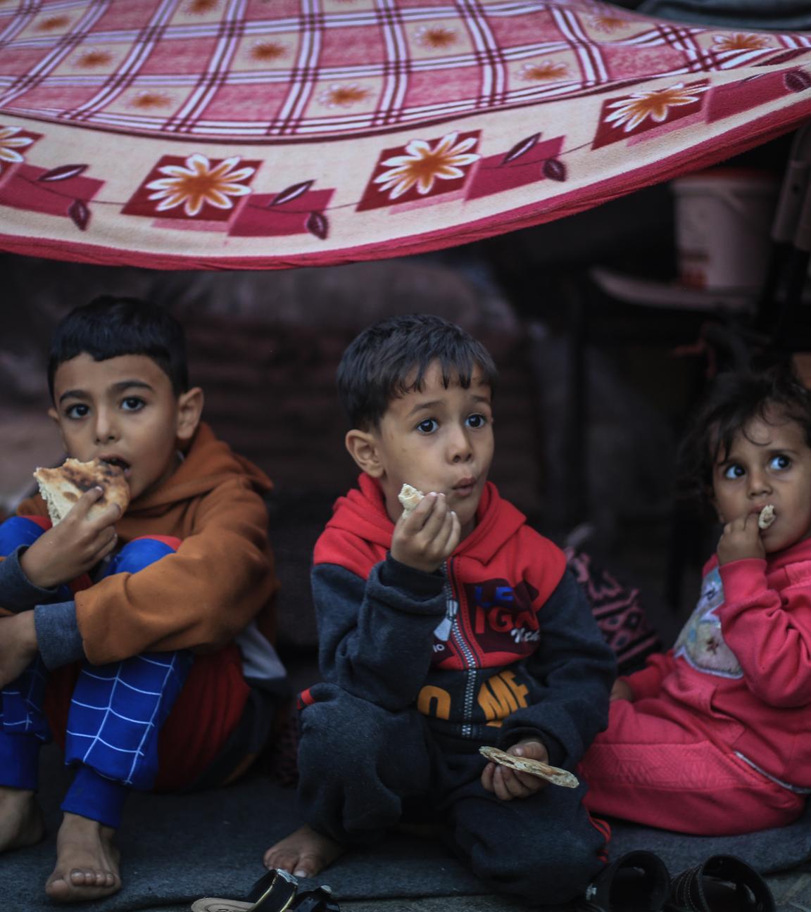 Drei Kinder sitzen in einer Schule in Chan Yunis im südlichen Gazastreifen.