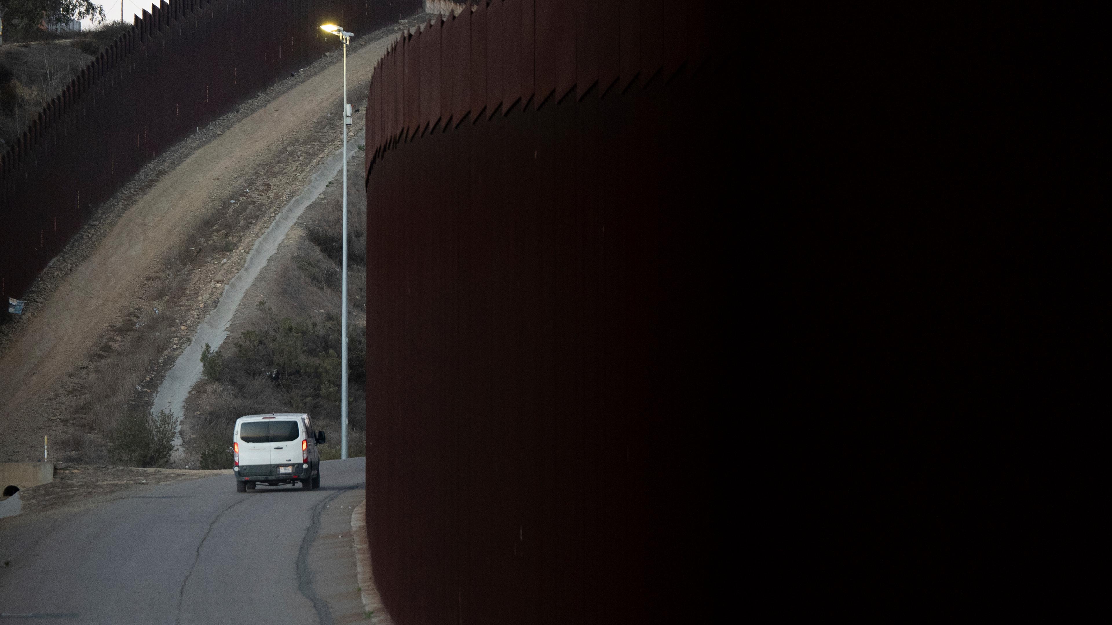 Auto fährt neben Grenzzaun zwischen USA und Mexiko