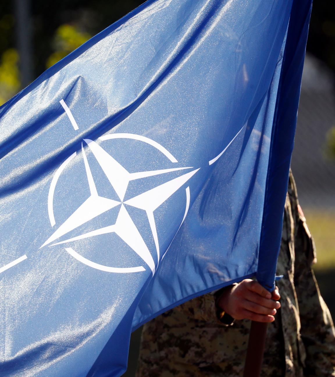 Ein Soldat hält eine Flagge der Nato auf einer Militärbasis in Lettland.