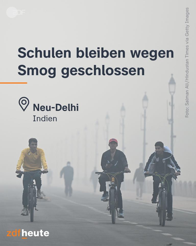 Männliche Jugendliche fahren mit dem Fahrrad auf einer Straße durch Smog, darüber die Überschrift: Schulen bleiben wegen Smog geschlosen, Ortsmarke: Neu-Delhi, Indien