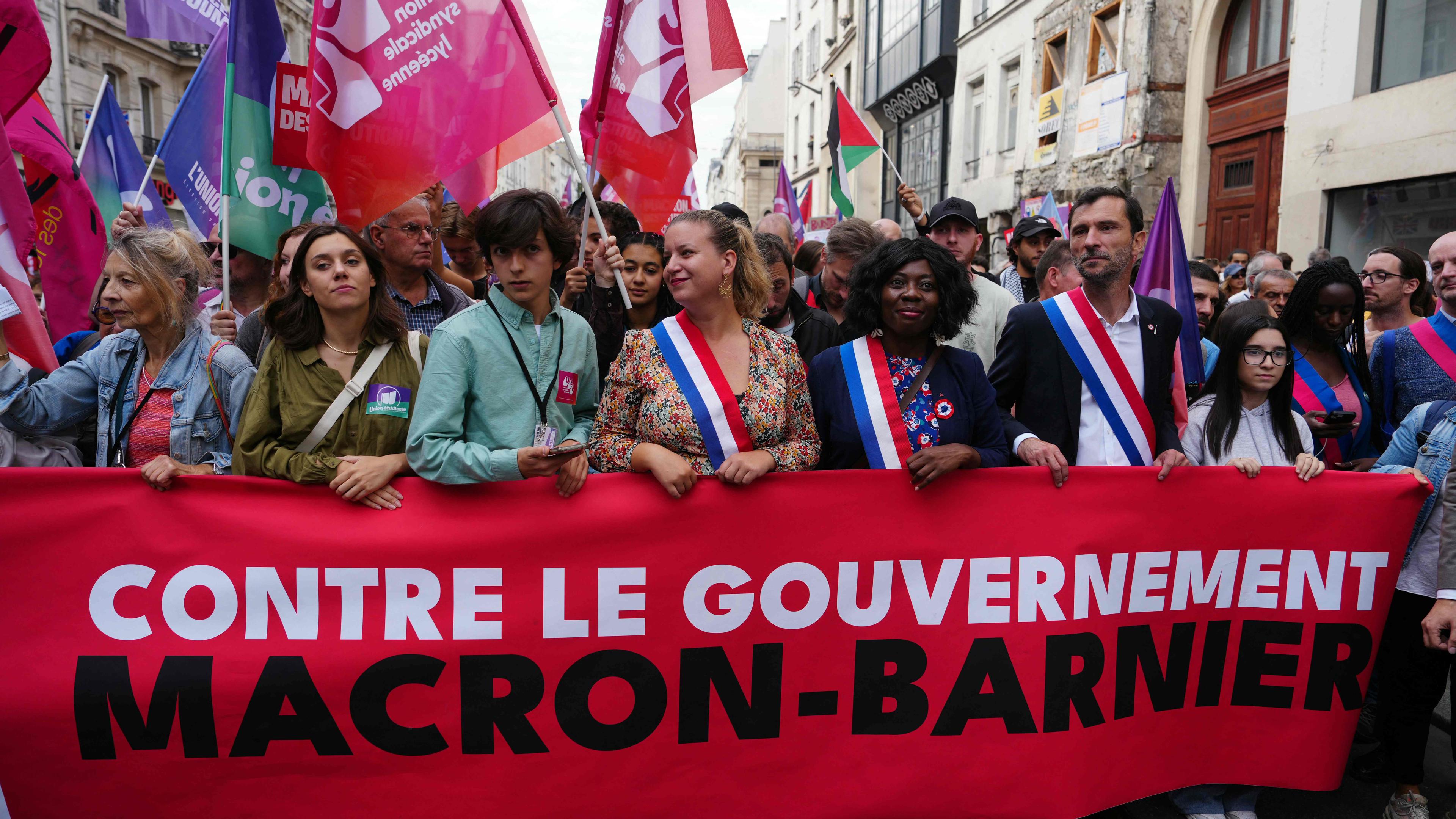 Vorsitzende der Fraktion La France Insoumise - Nouveau Front Populaire Mathilde Panot (C), La France Insoumise - Nouveau Front Populaire's MP Daniele Obono (C-R) und La France Insoumise - Nouveau Front Populaire's MP Arnaud Saint-Martin (R) gehen während eines Protests gegen die „Macron-Barnier“-Regierung am September 21, 2024 in Paris.