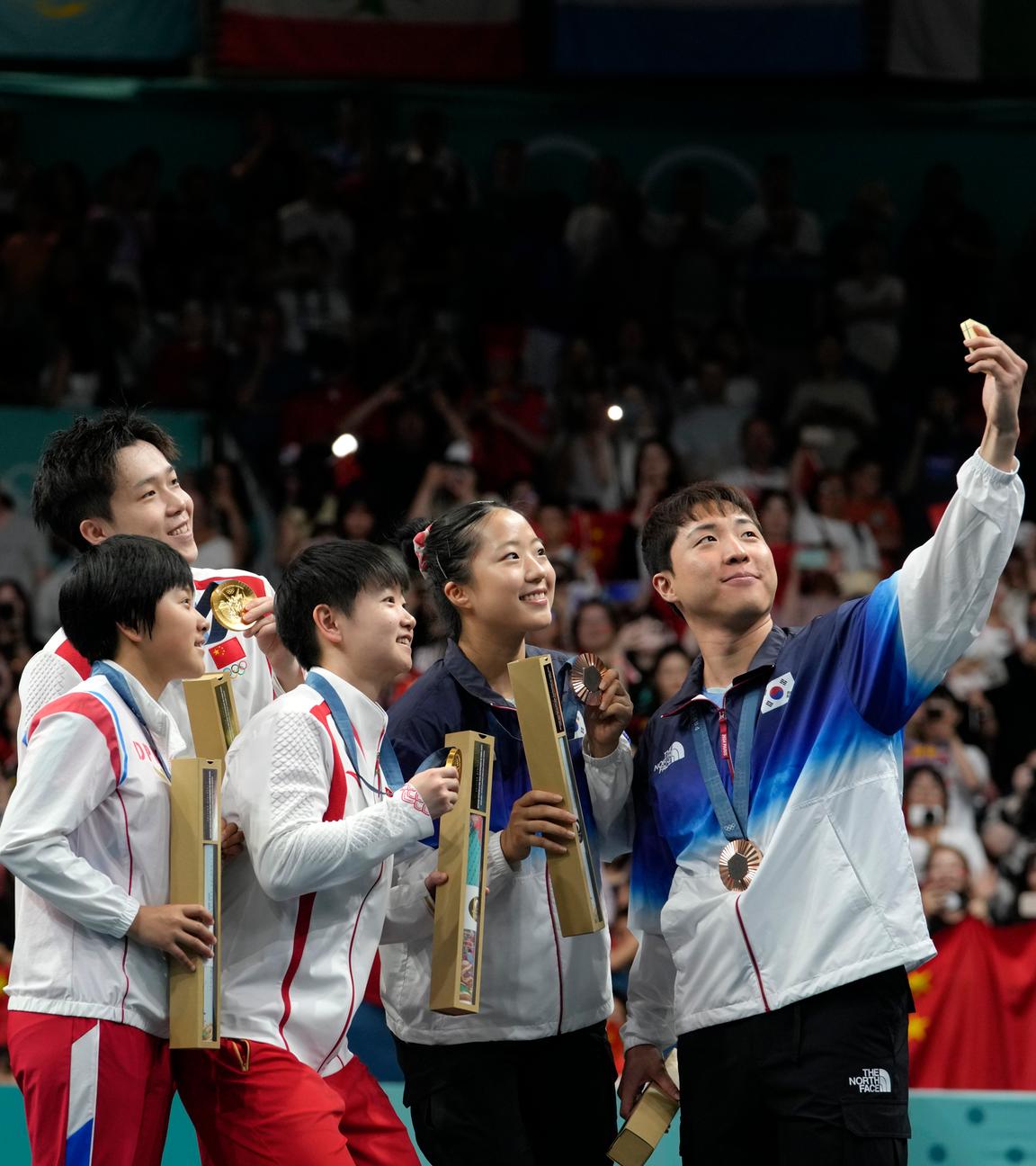 Die Olympiasieger Wang Chuqin und Sun Yingsha aus China, feiern mit den Zweitplatzierten Kim Kum Yong und Ri Jong Sik aus Nordkorea und den Dritten Shin Yubin/Lim Jonghoon aus Südkorea.