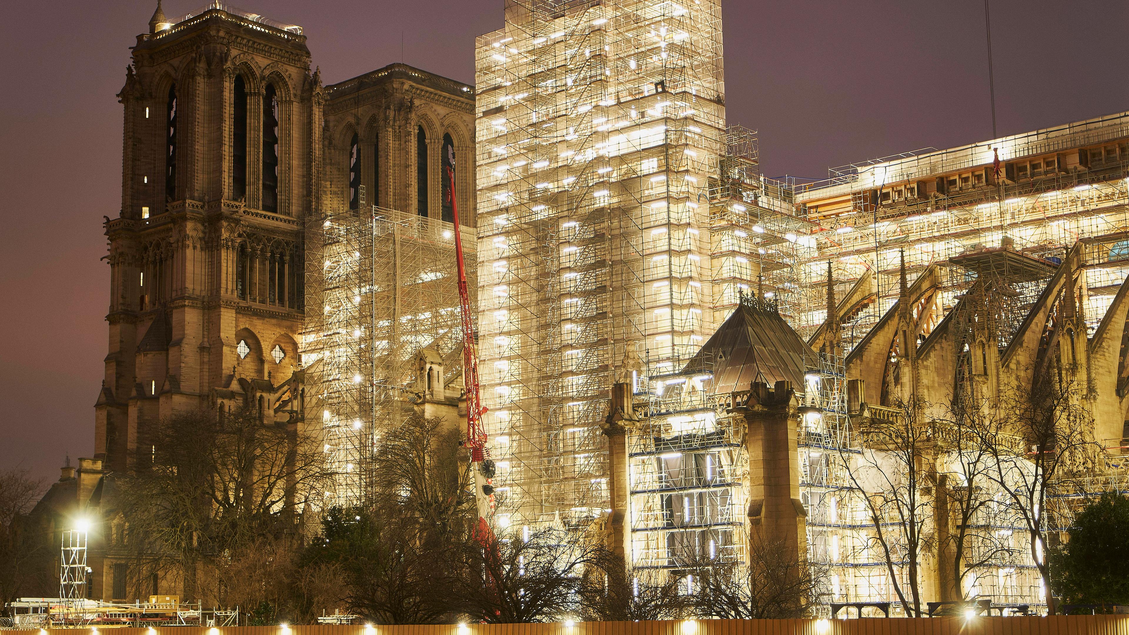 Notre Dame de Paris mit beleuchteten Gerüsten bei Nacht.