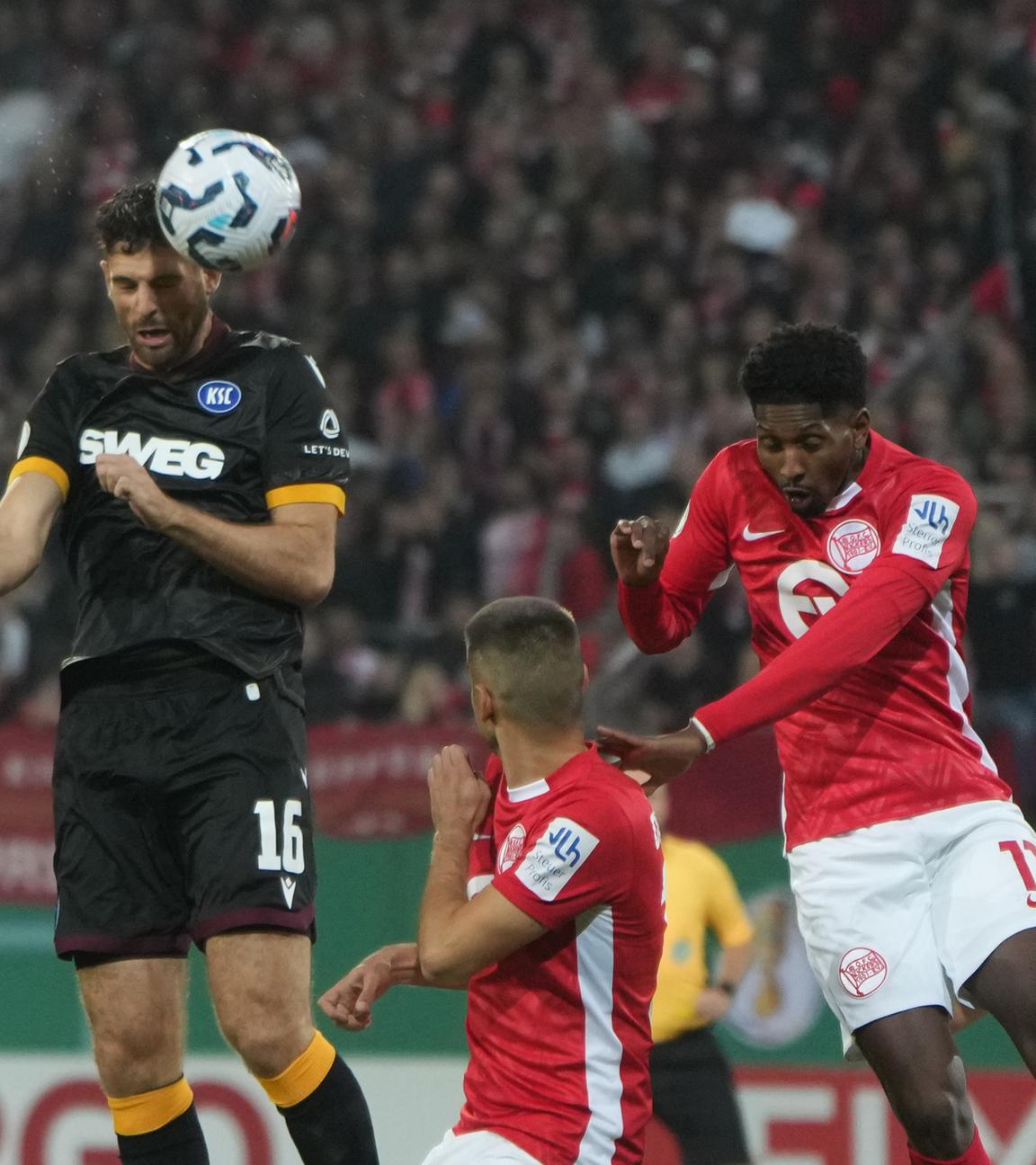 Karlsruhes Luca Pfeiffer (l) und Offenbachs Boubacar Barry (3.vl) kämpfen um den Ball. 