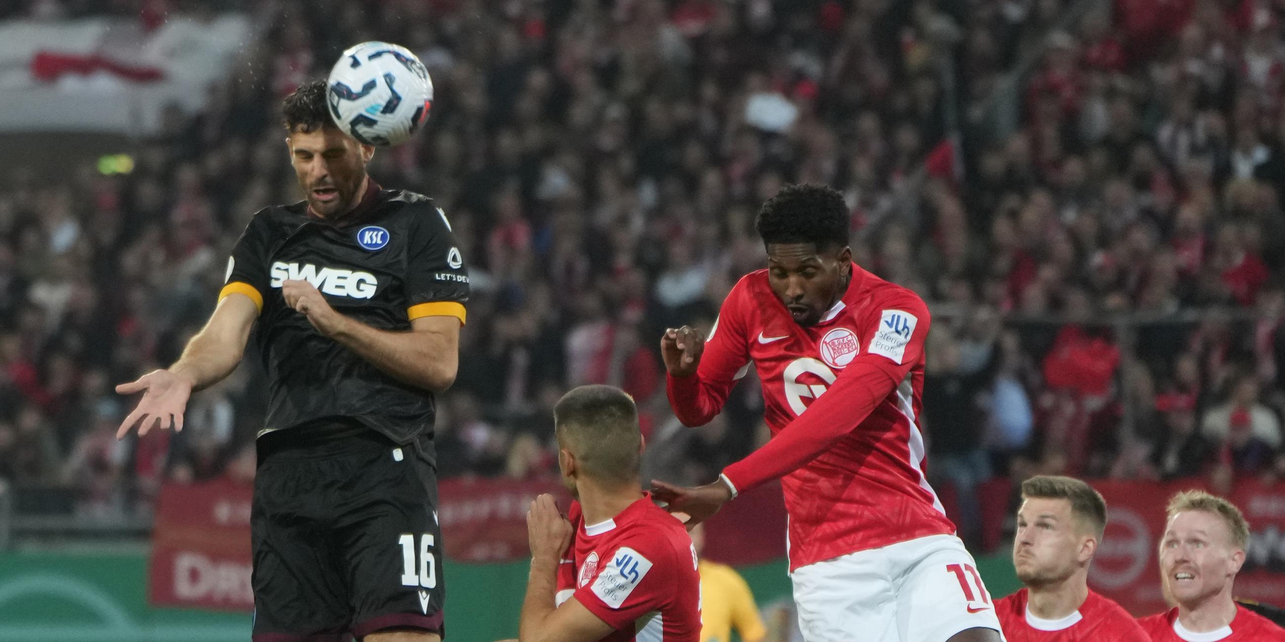 Karlsruhes Luca Pfeiffer (l) und Offenbachs Boubacar Barry (3.vl) kämpfen um den Ball. 