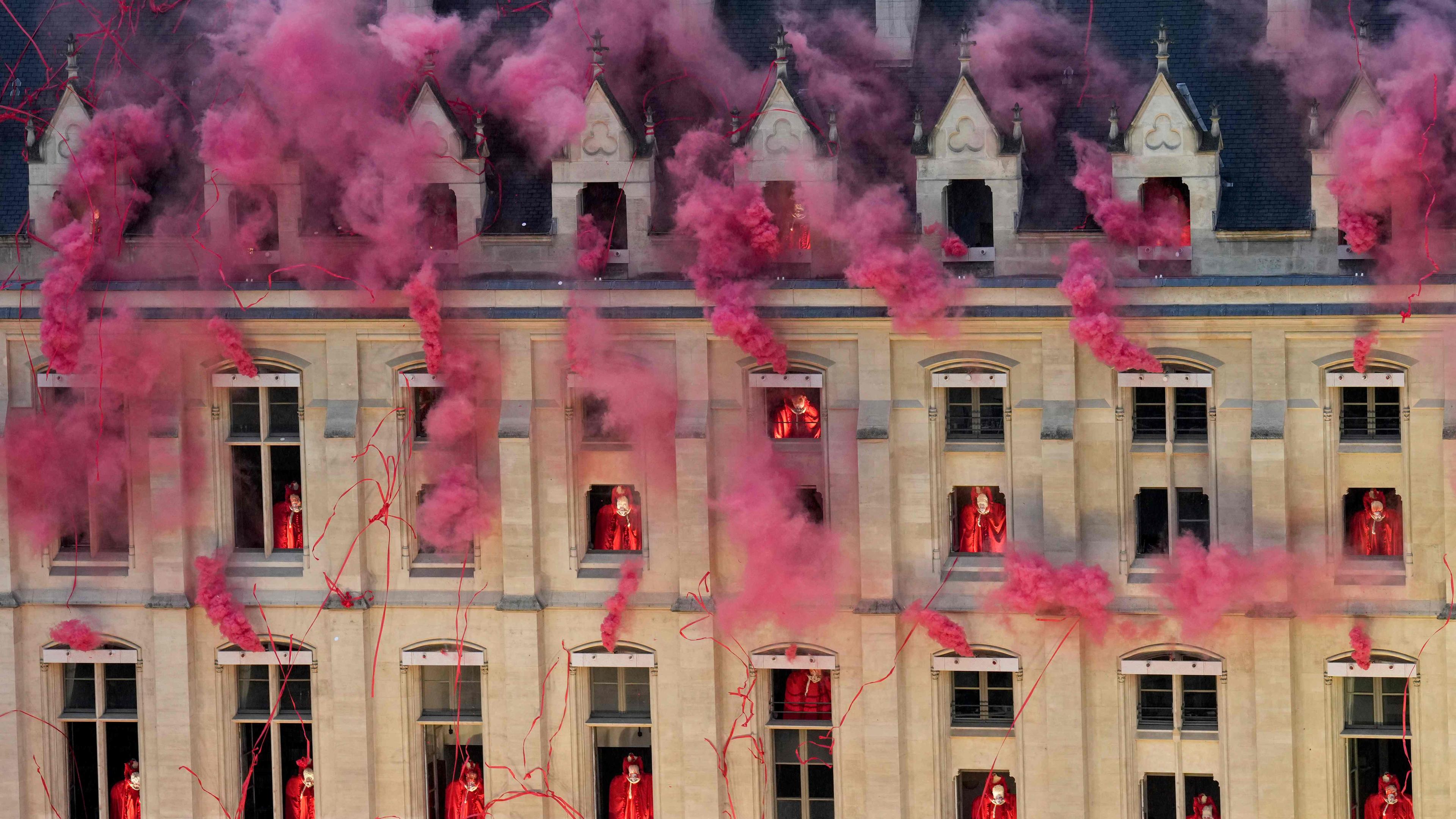 Roter Rauch kommt aus Fenstern eines Gebäudes in Paris als Teil einer Performance der Eröffnungsfeier der Olympischen Spiele.