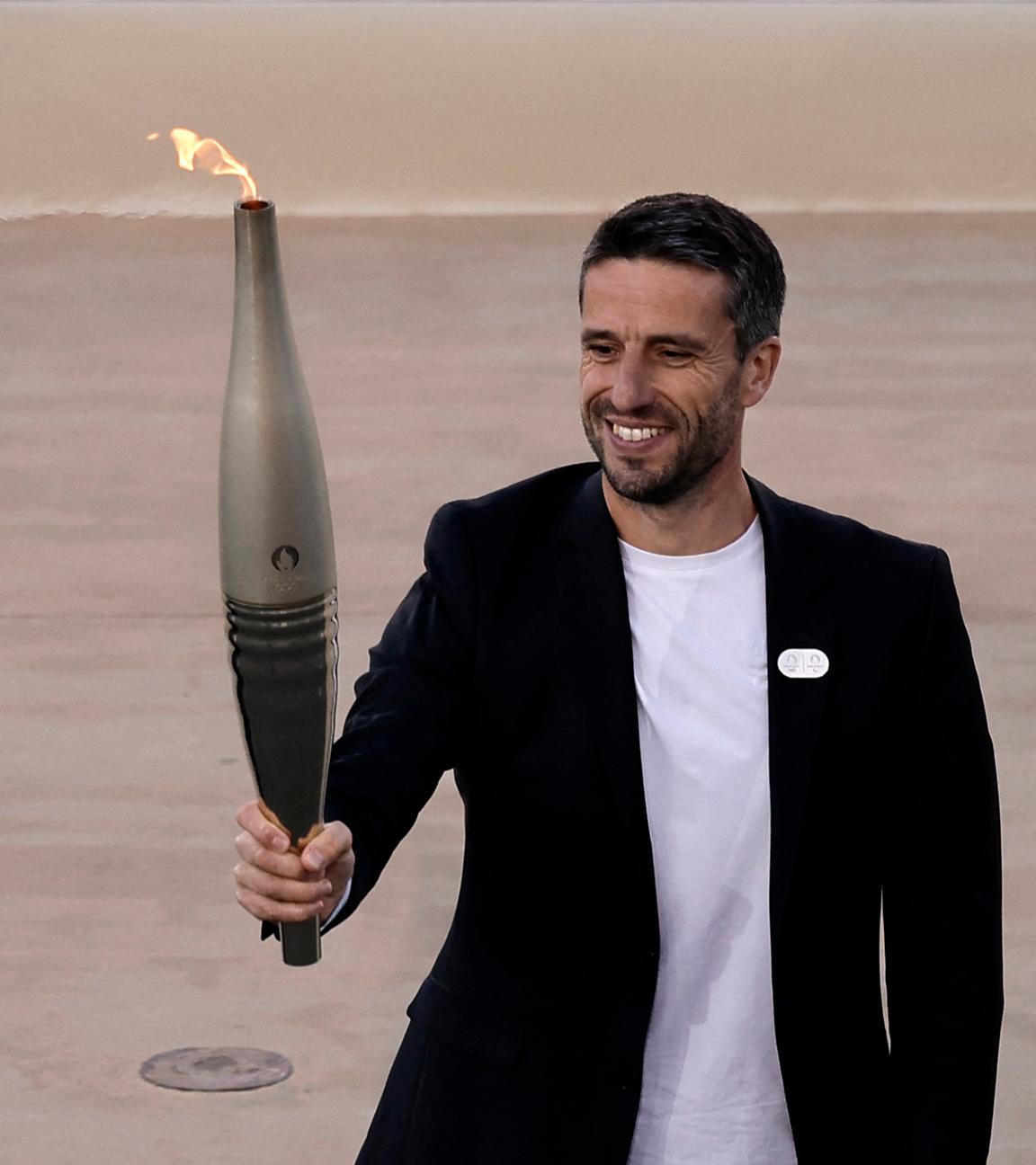 Tony Estanguet, Präsident von Paris 2024, hält eine Fackel mit der olympischen Flamme.