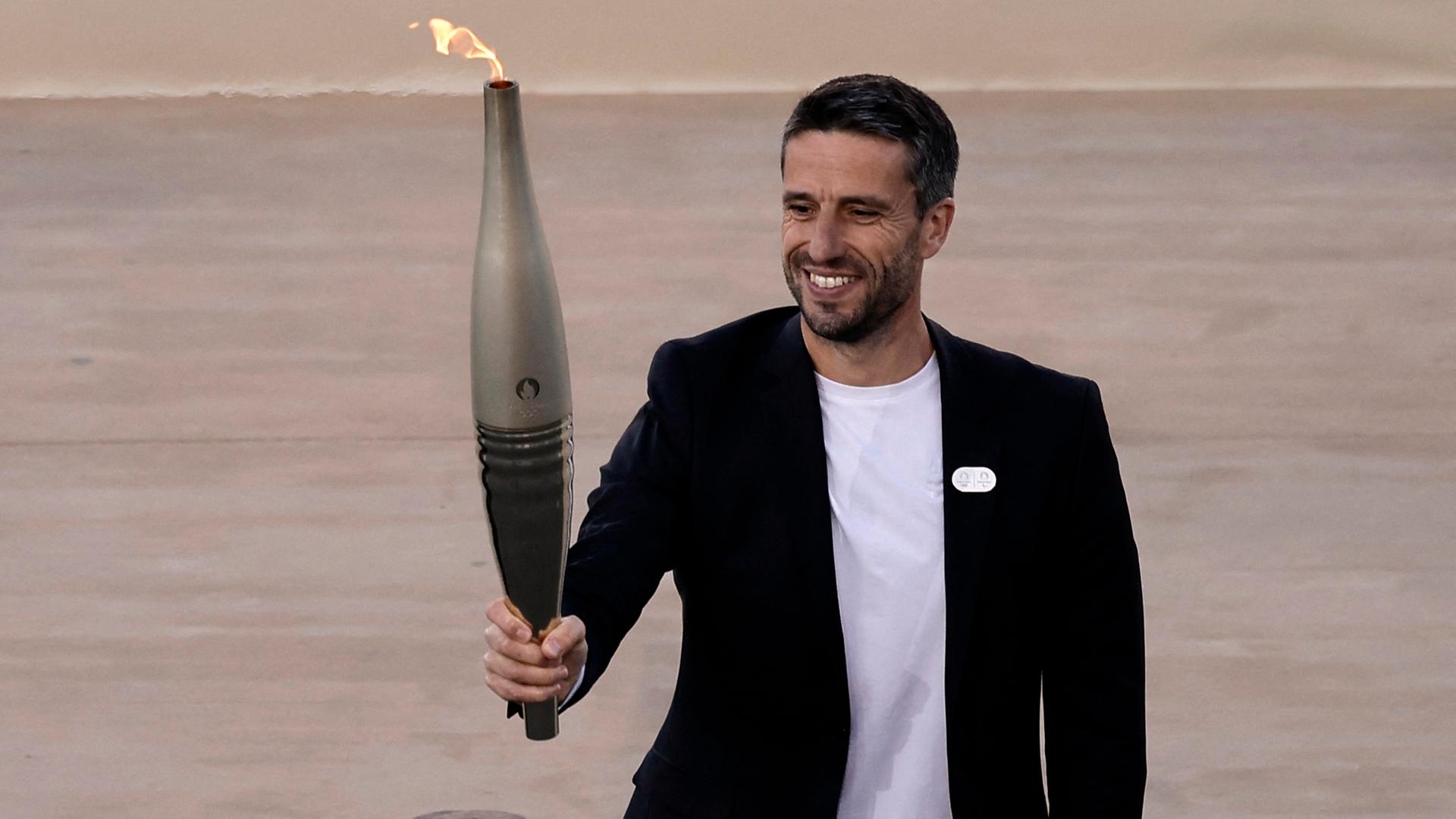 Tony Estanguet, Präsident von Paris 2024, hält eine Fackel mit der olympischen Flamme.