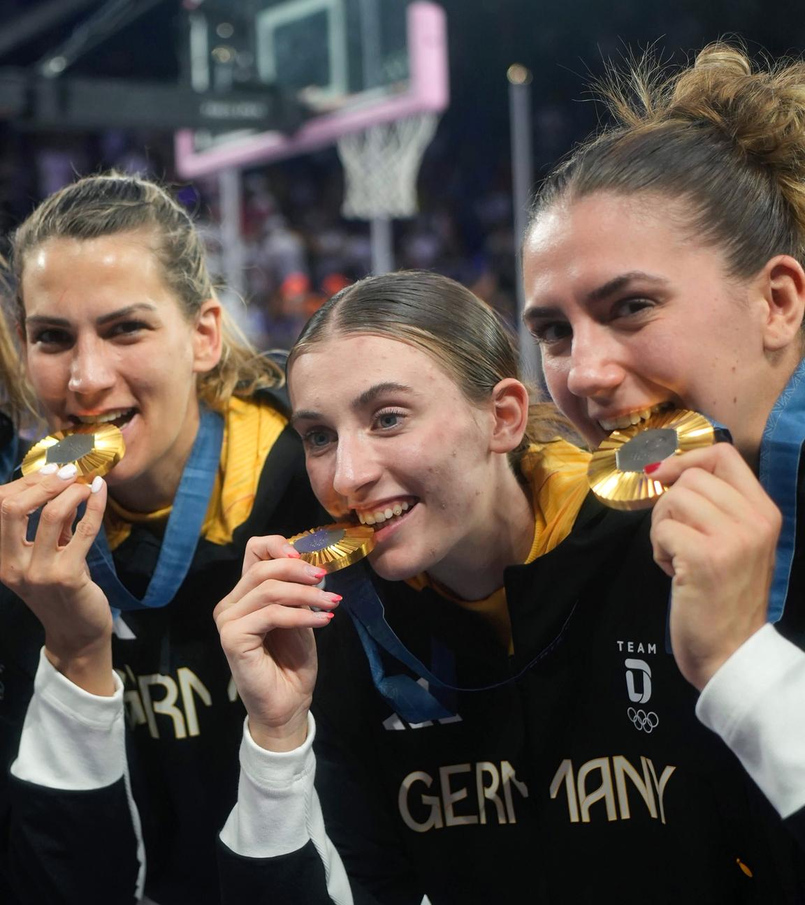 Svenja Brunckhorst (l-r), Sonja Greinacher, Elisa Mevius und Marie Reichert beißen nach der Siegerehrung auf ihre Goldmedaille. 