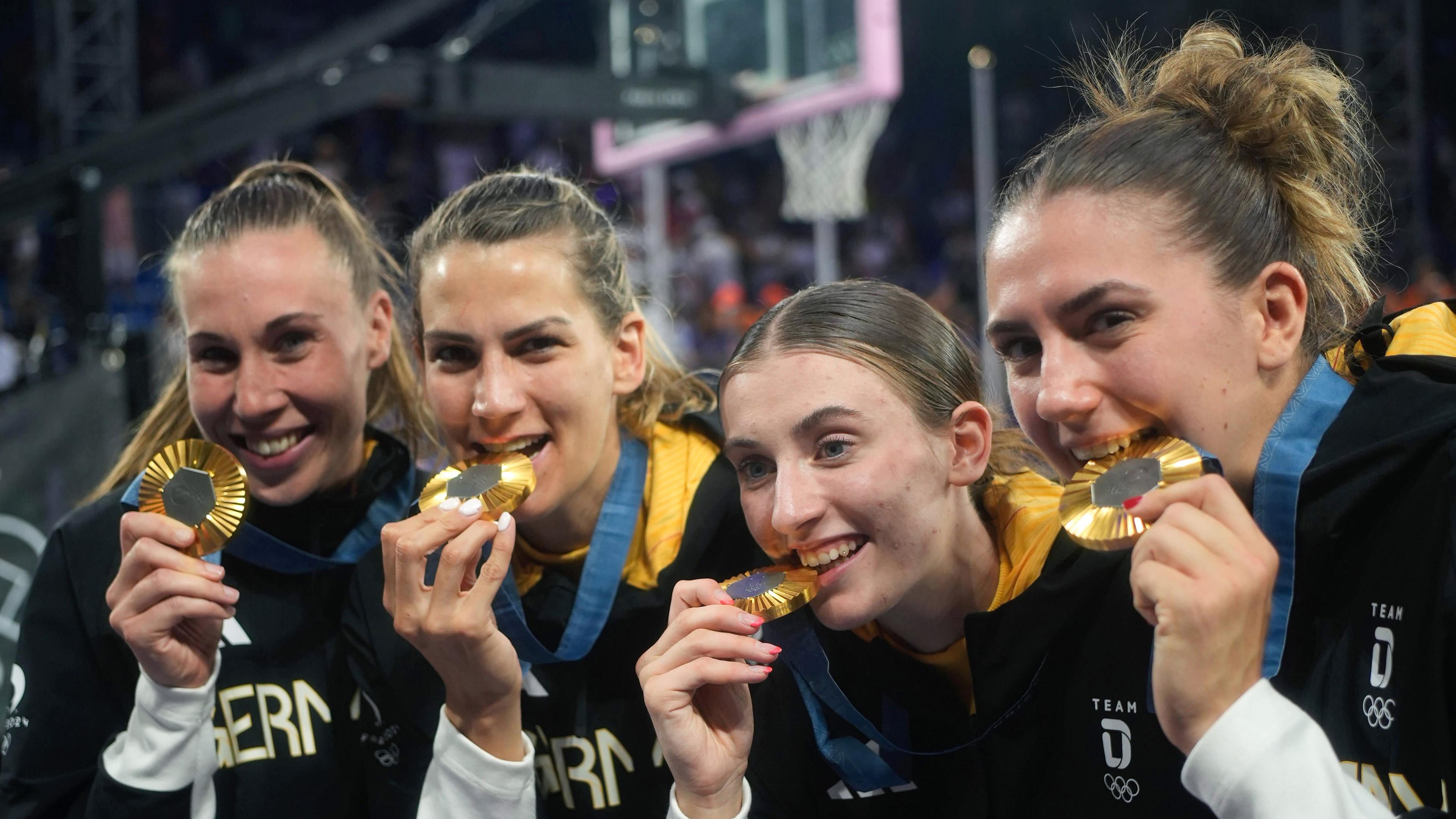 Svenja Brunckhorst (l-r), Sonja Greinacher, Elisa Mevius und Marie Reichert beißen nach der Siegerehrung auf ihre Goldmedaille. 