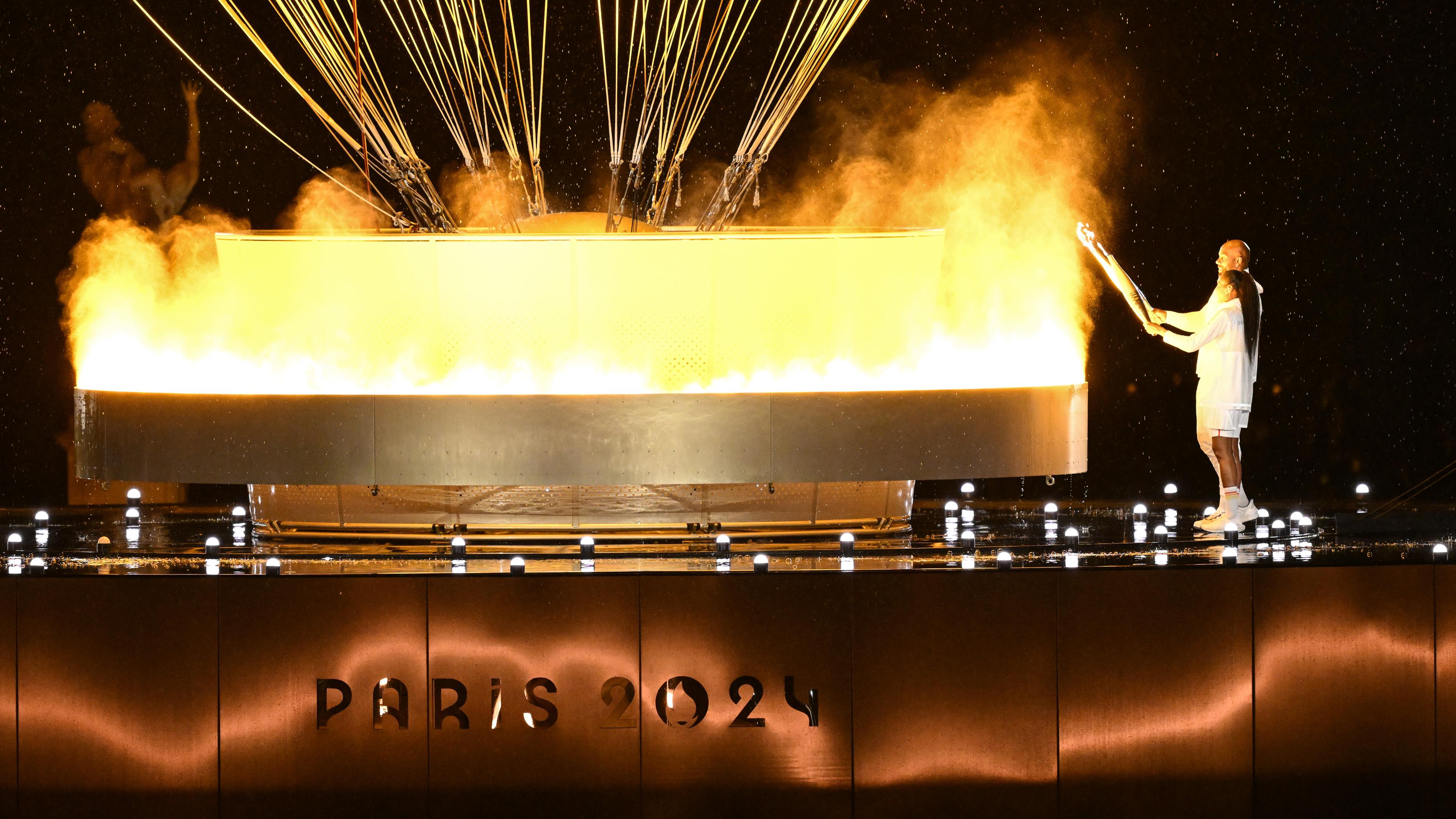 Marie-Jose Perec und Teddy Riner entzünden das olympische Feuer in Paris.