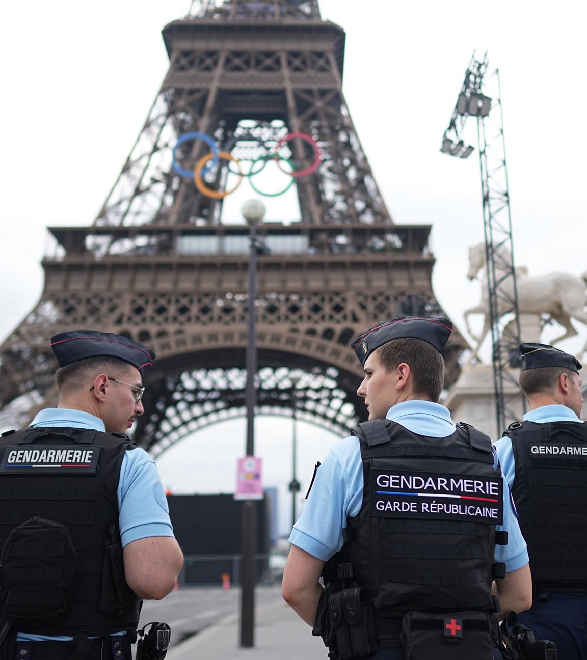 Frankreich, Paris: Vor den Olympischen Sommerspielen, Paris 2024, Polizisten laufen am Eiffelturm entlang.