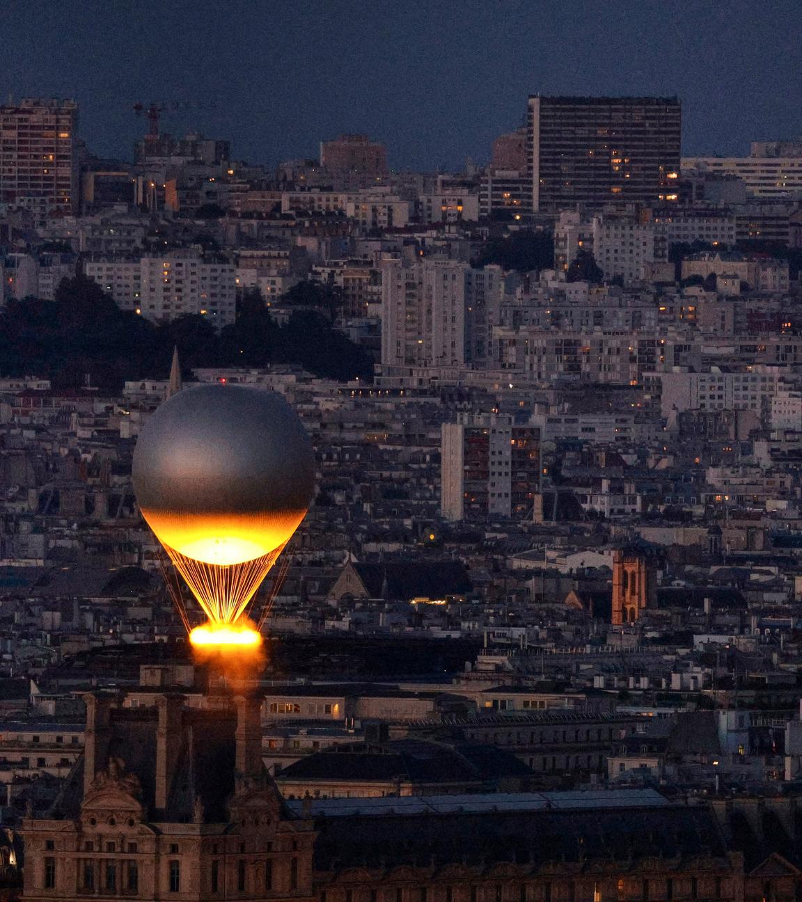 Der Kessel mit dem Olympischen Feuer fliegt an einem Ballon befestigt über Paris, vom Eiffelturm aus gesehen.