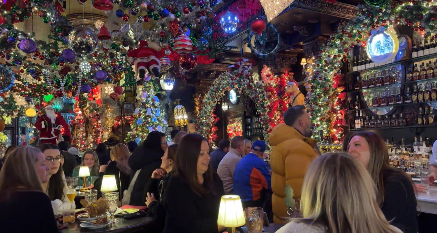 In der weihnachtlich geschmückten "Oscar Wilde" Bar sitzen Gäste.