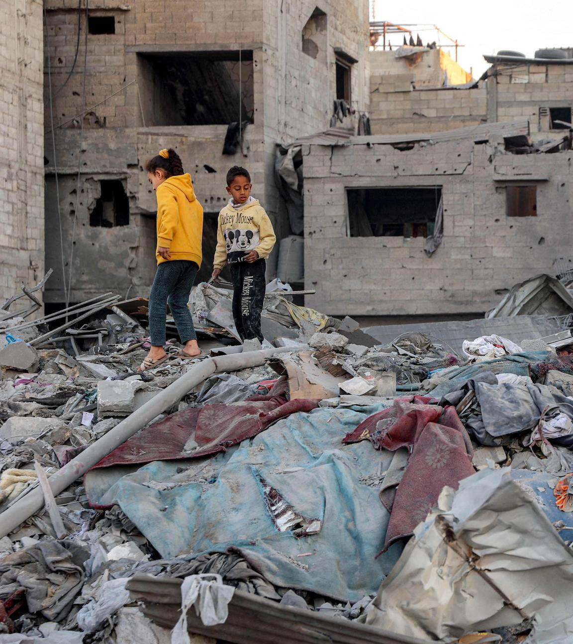 Children walk through debris and rubble at the site of Israeli bombardment on a residential block in Jalaa Street in Gaza City