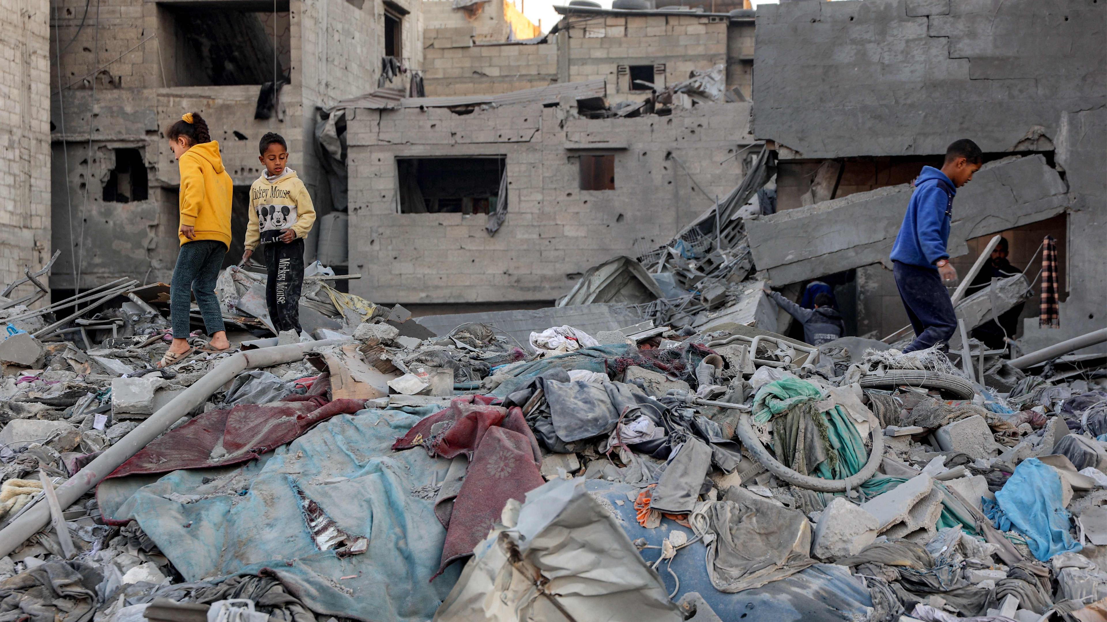 Children walk through debris and rubble at the site of Israeli bombardment on a residential block in Jalaa Street in Gaza City