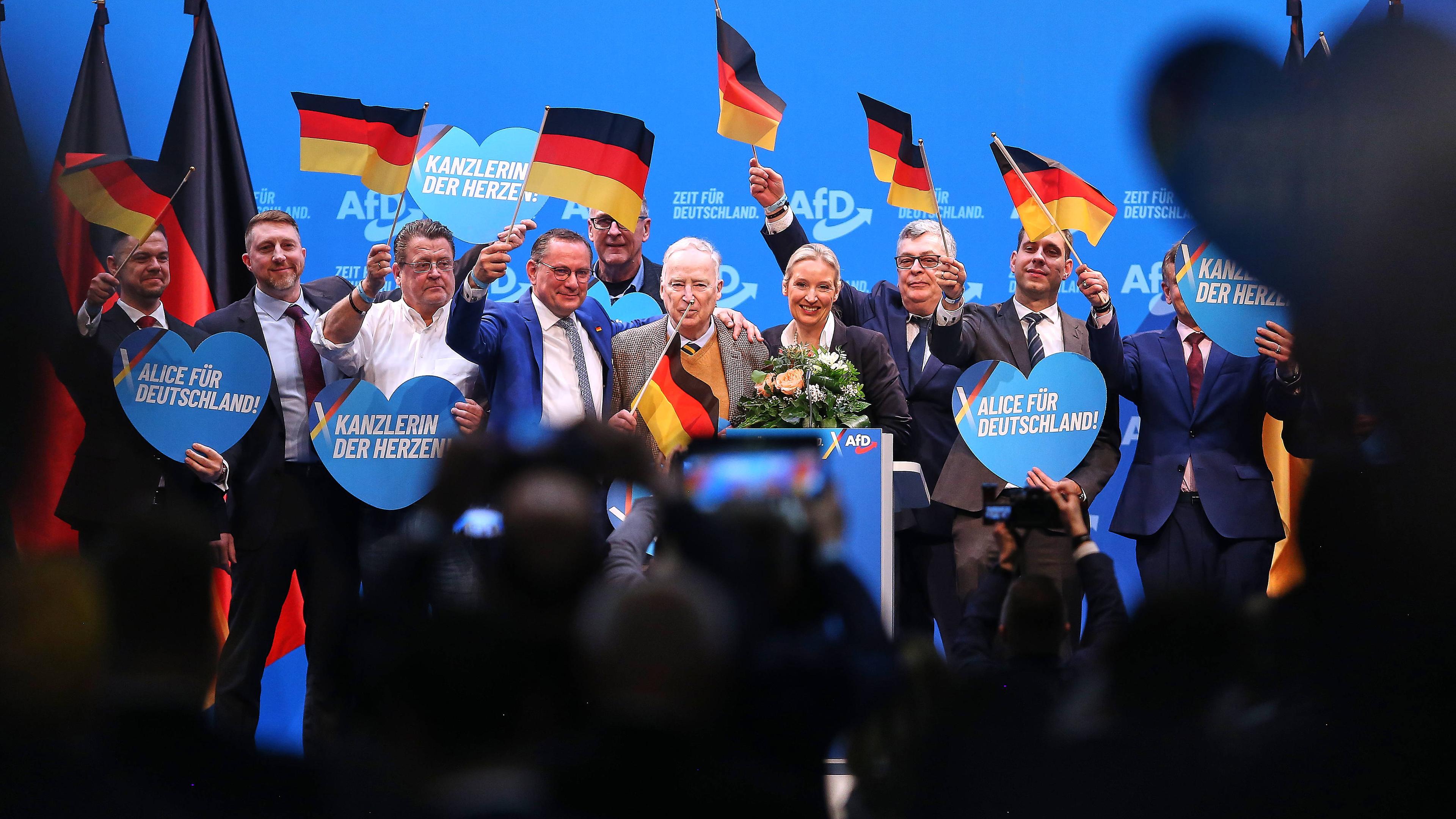 Teile der AfD-Spitze stehen auf einer Bühne auf dem Parteitag in Riesa und schwenken kleine Deutschland-Fahnen.