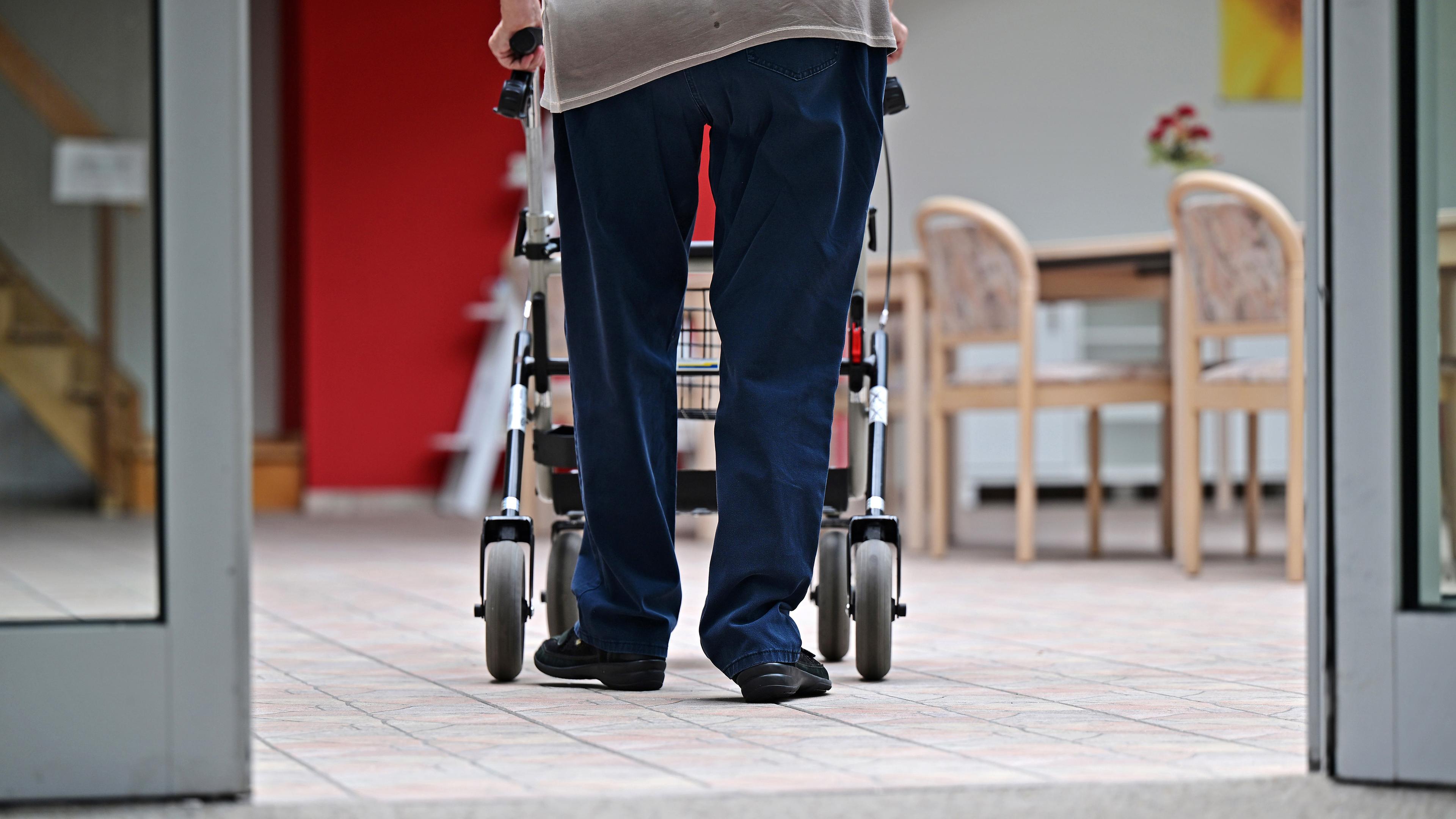 Ein Bewohner eines Pflegezentrums geht mit dem Rollator durchs Haus (Archivbild)