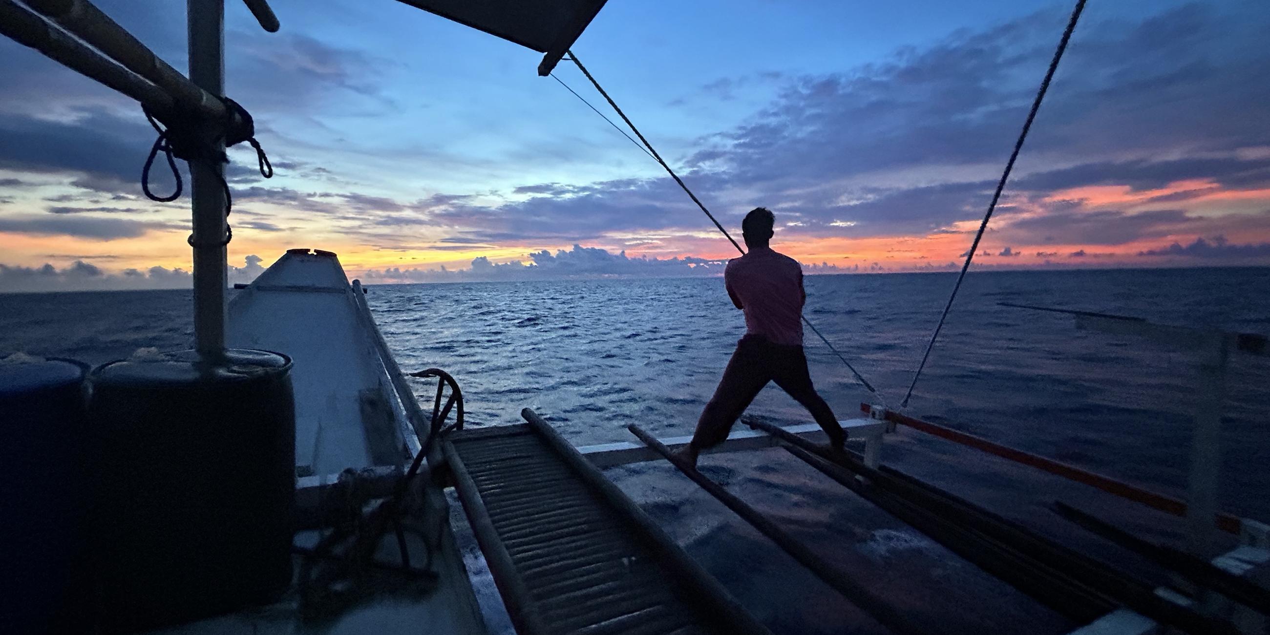 Ein Mann steht auf einem Boot und schaut auf das Meer hinaus.