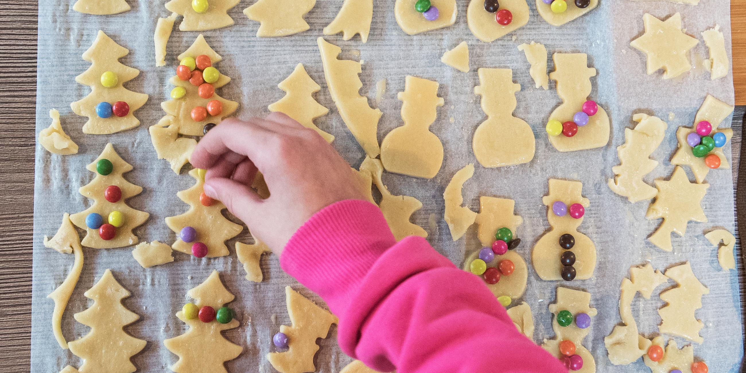 Weihnachtsplätzchen auf einem Backblech, die dekoriert werden