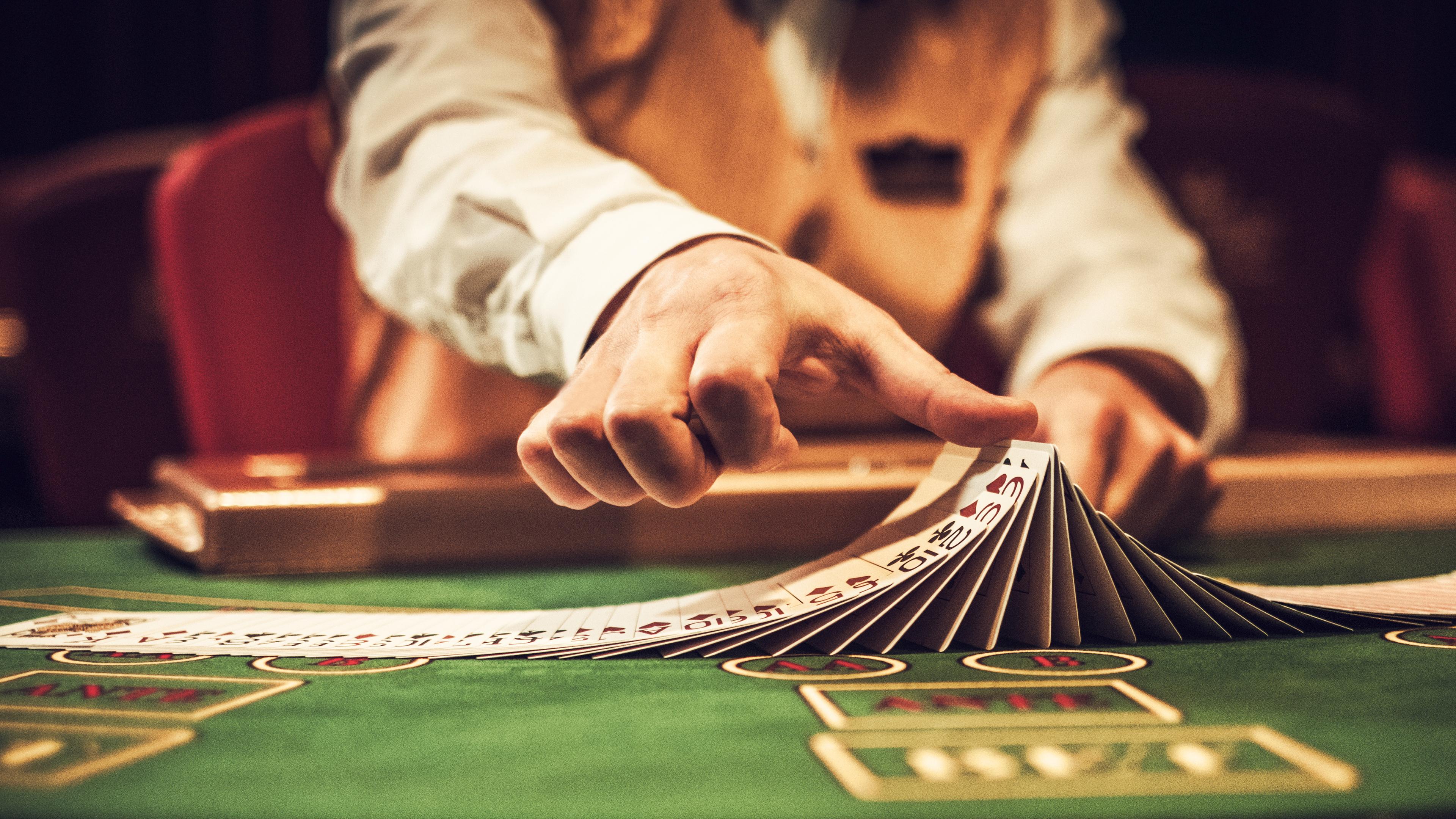 Nahaufnahme auf die Hände eines Croupiers. Sie mischen im Casino geübt Karten.