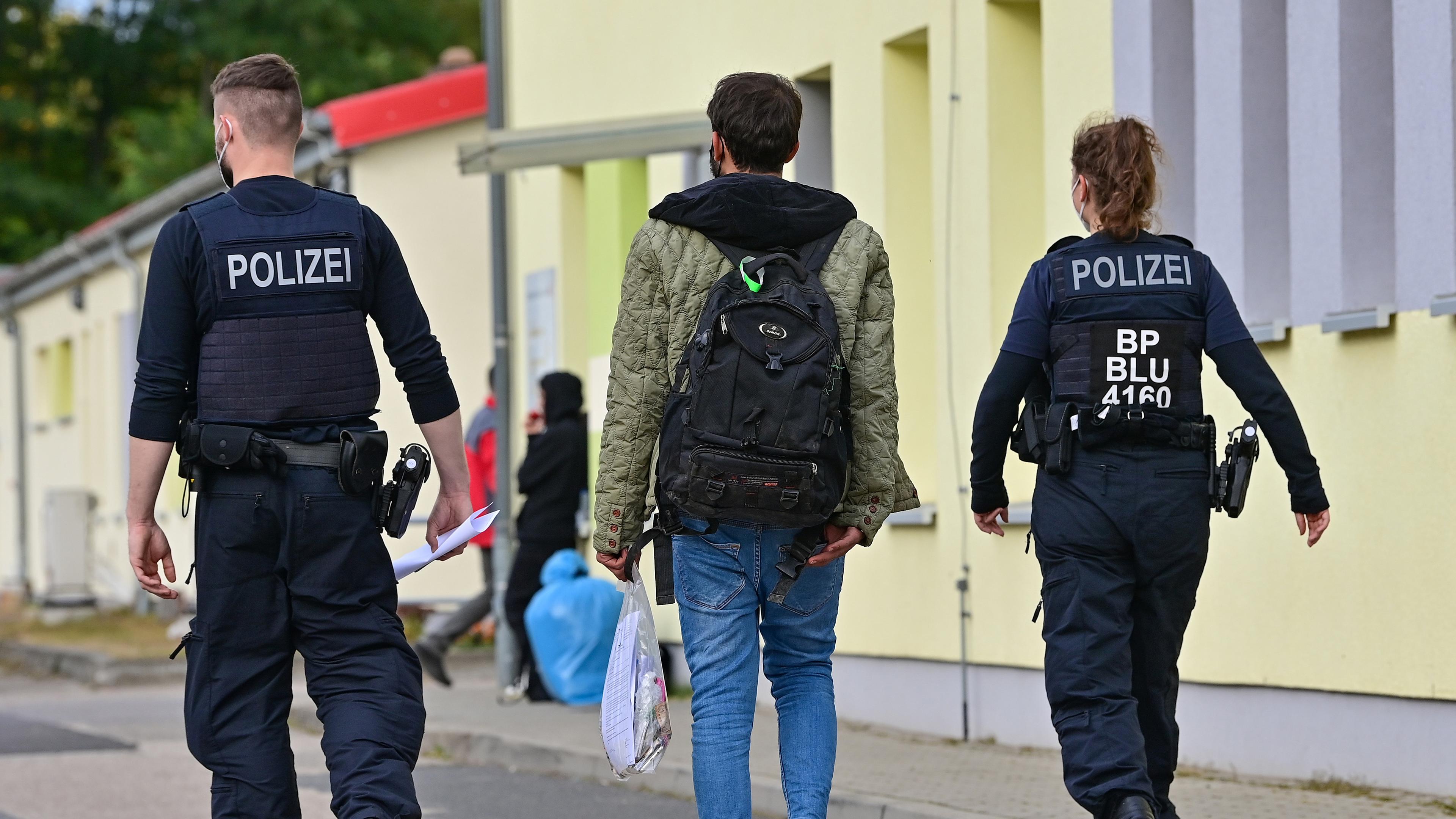 Zwei Beamte der Bundespolizei begleiten einen Flüchtling