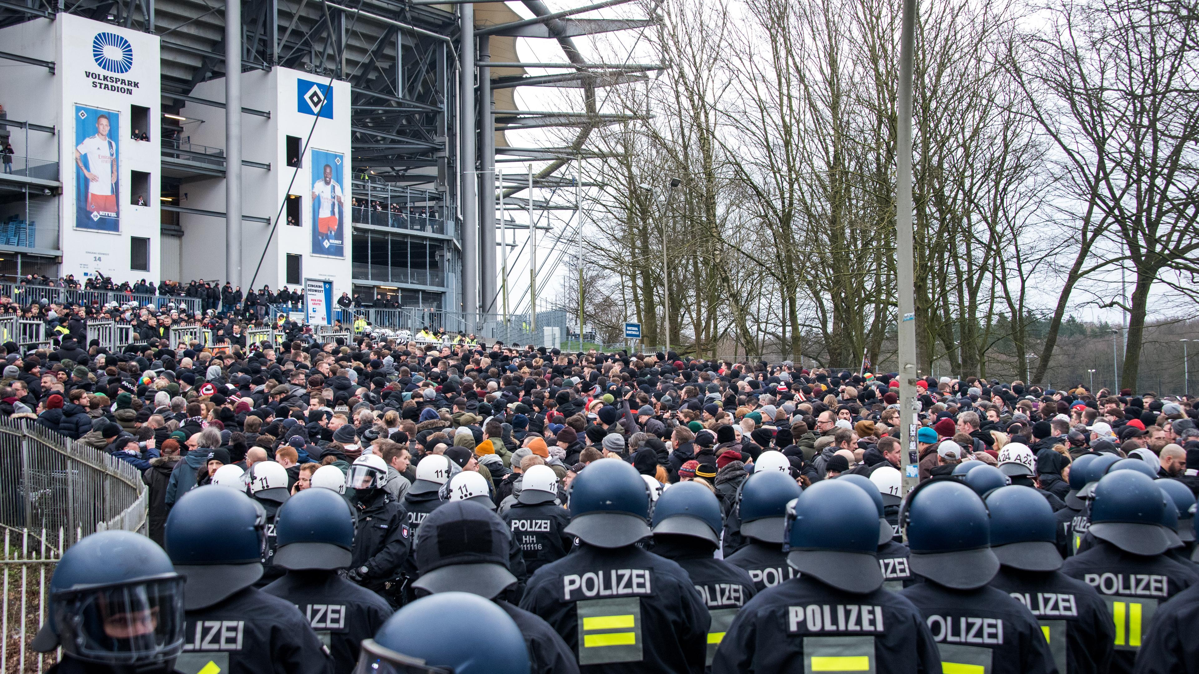 Fußballfans kommen von der Polizei begleitet am Stadion an.