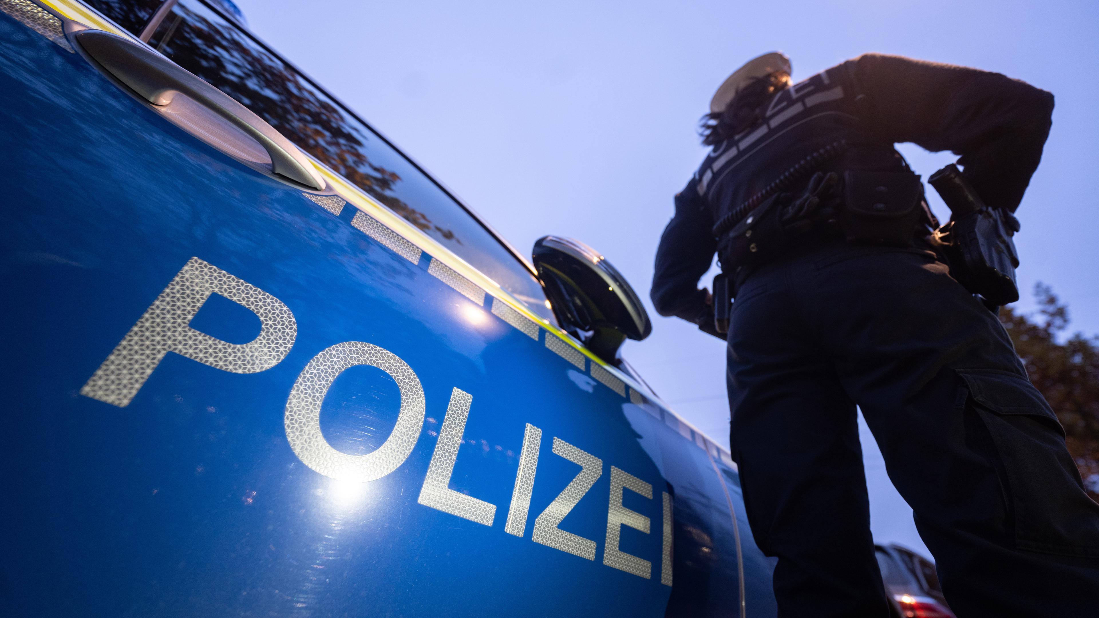 Baden-Württemberg, Stuttgart: Eine Polizistin steht neben einem Polizeifahrzeug