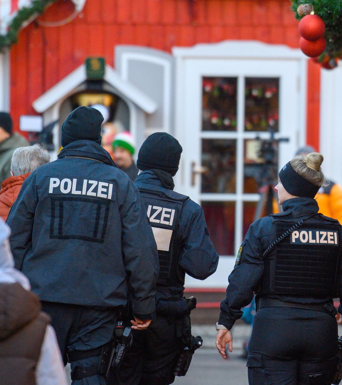 Polizisten und Passanten gehen über den geschlossenen Magdeburger Weihnachtsmarkt