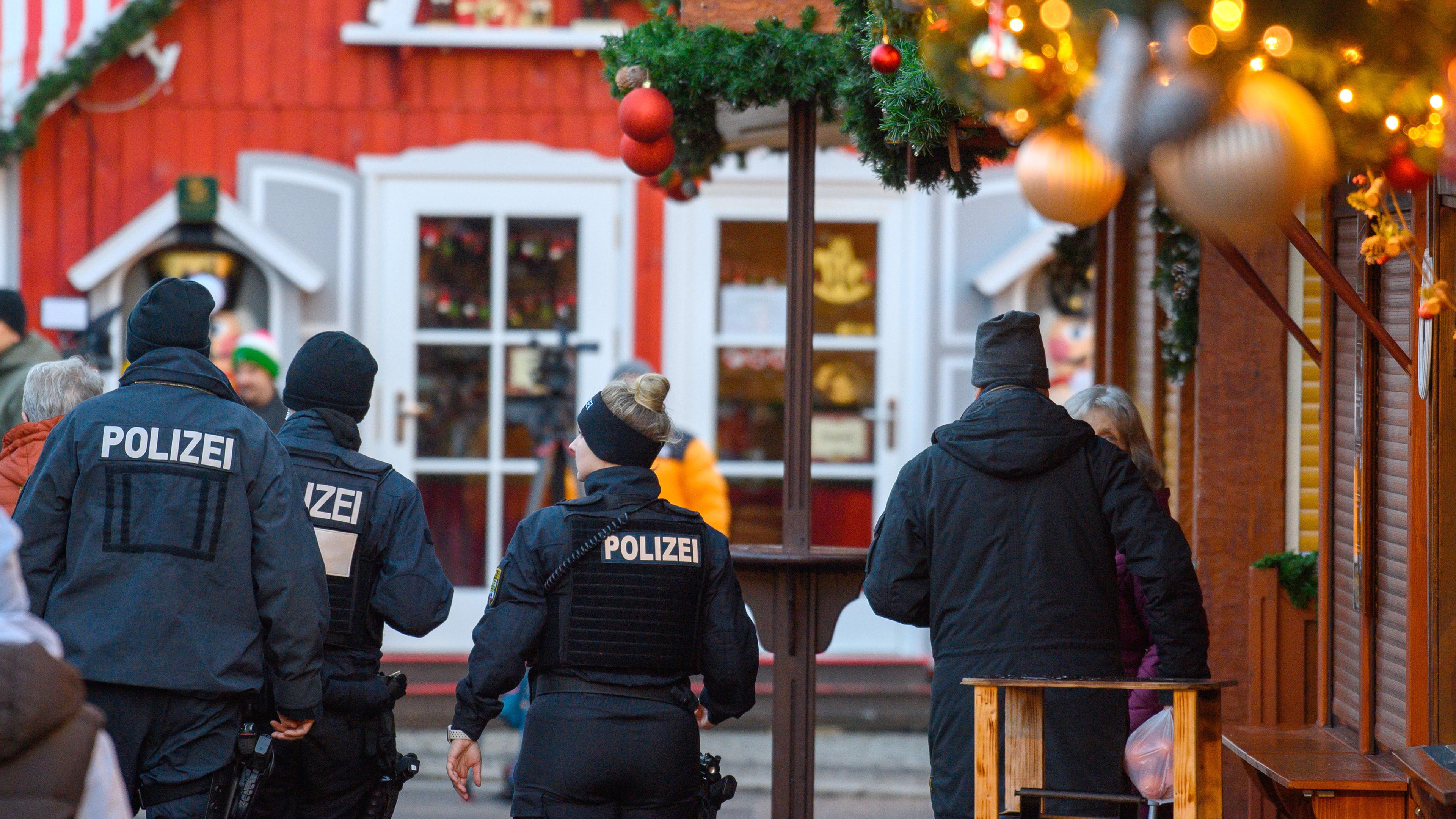 Polizisten und Passanten gehen über den geschlossenen Magdeburger Weihnachtsmarkt