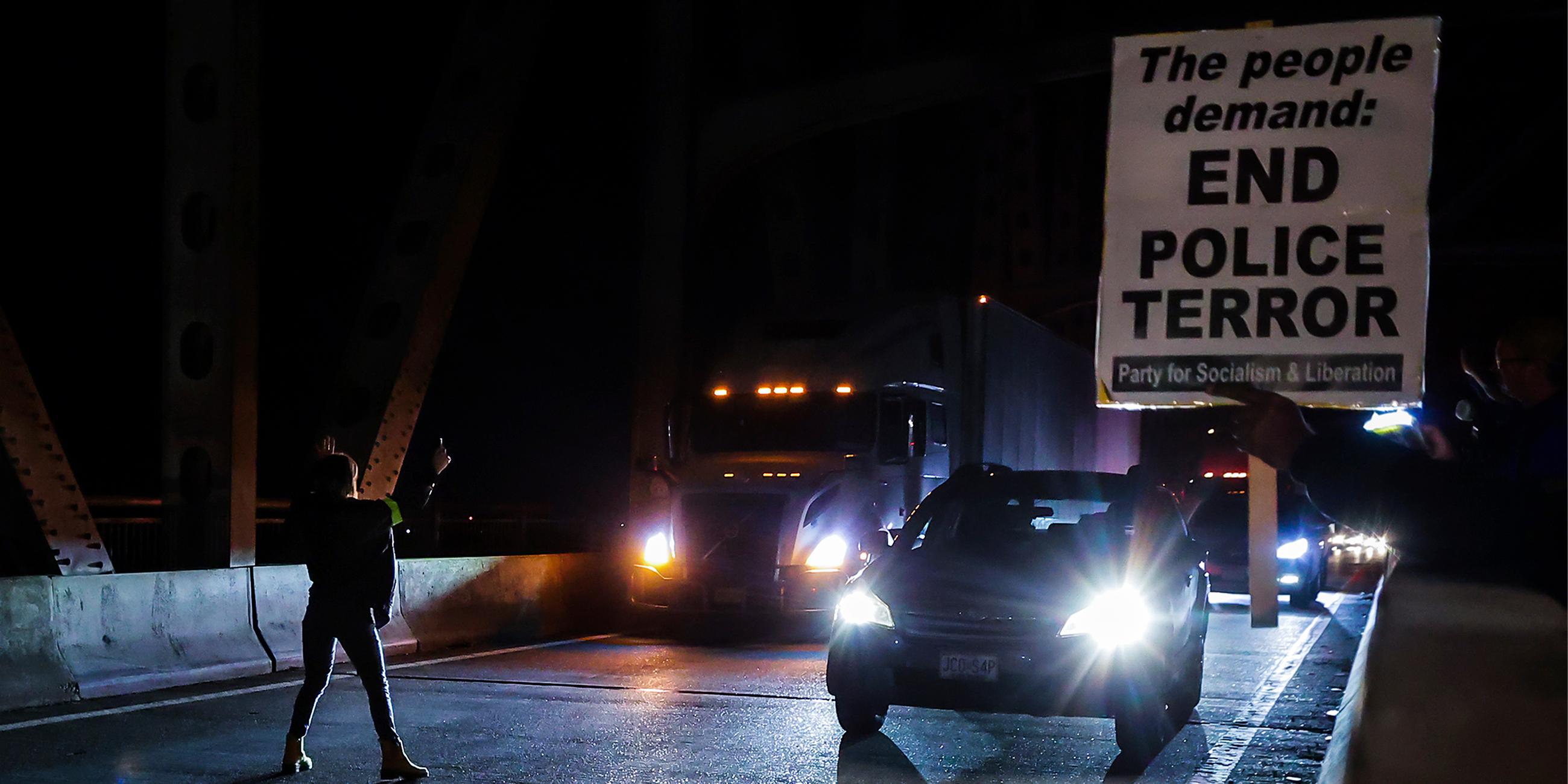 Auf einer Straße in den USA halten nachts Autos an, da Demonstranten den Verkerh stoppen.