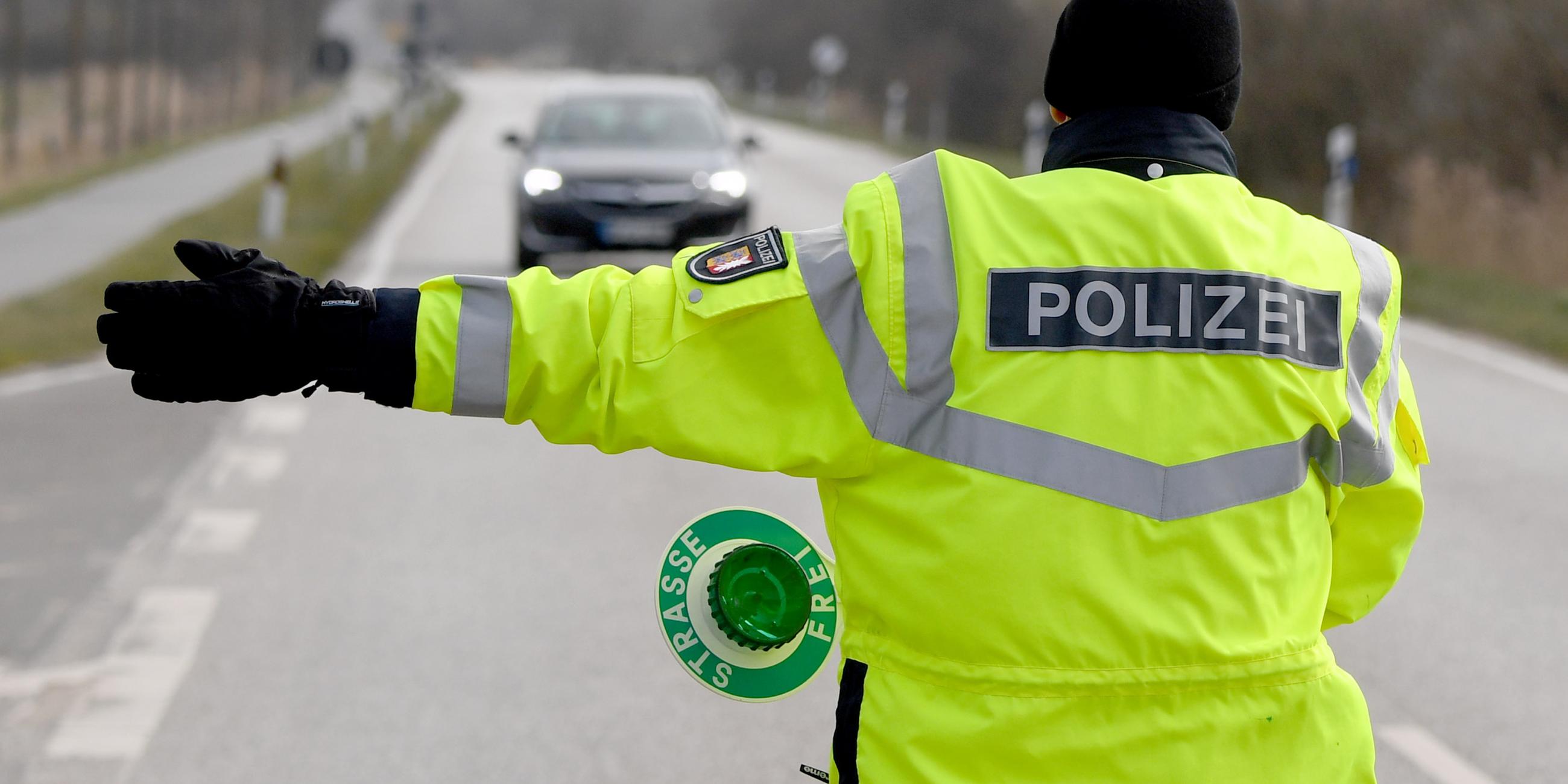 Ein Polizist winkt einen Autofahrer zu einer Kontrollstelle