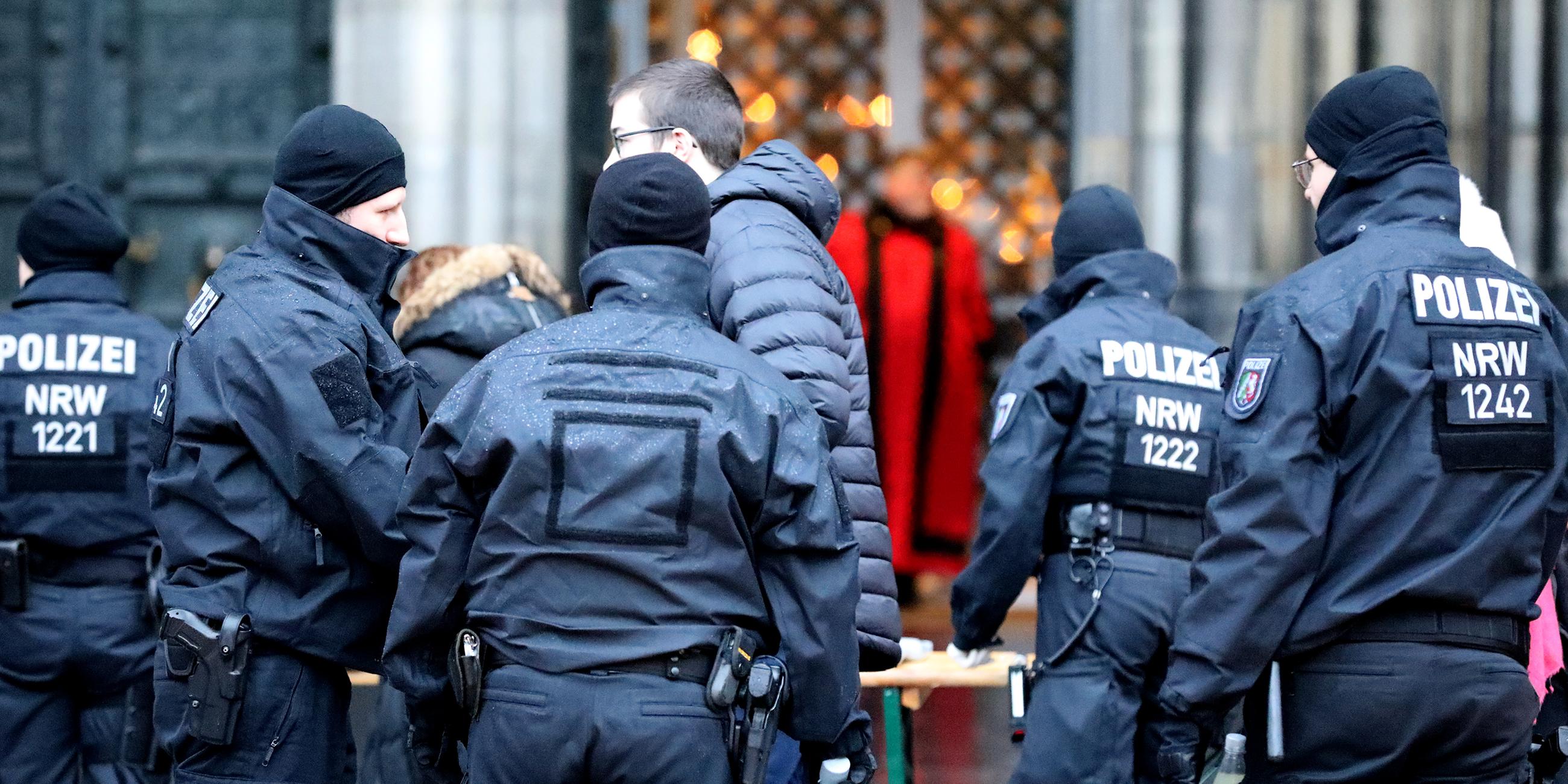 Polizisten stehen vor Beginn des Pontifikalamt vor dem Kölner Dom