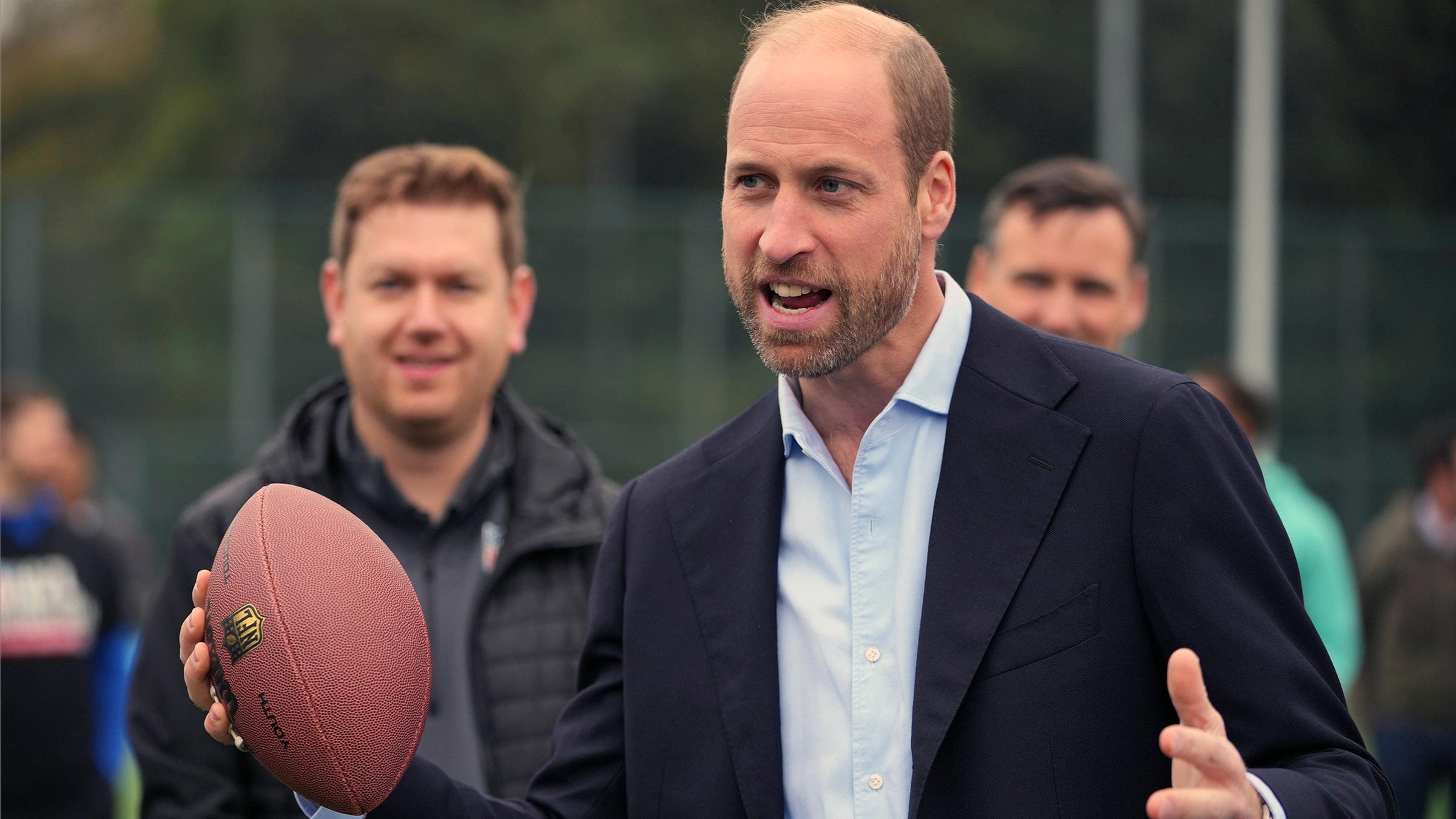 Prinz William mit einem Football in der Hand.