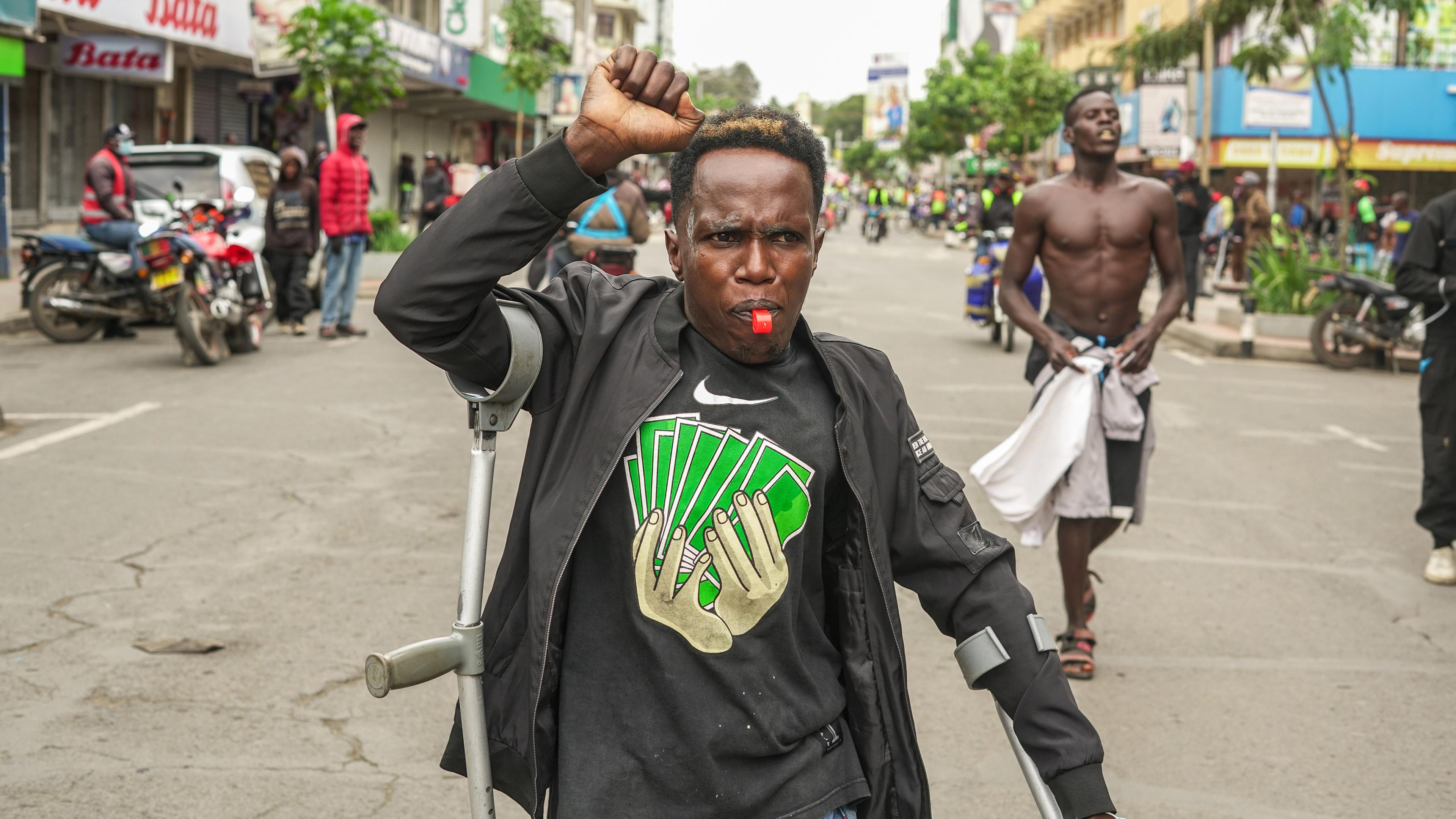 Ein Demonstrant hebt seine Faust, während er bei dem Protest gegen die Regierung eine Trillerpfeife bläst.