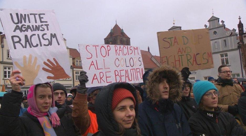 Protestierende halten Schilder hoch um gegen Rassismus zu protestieren.