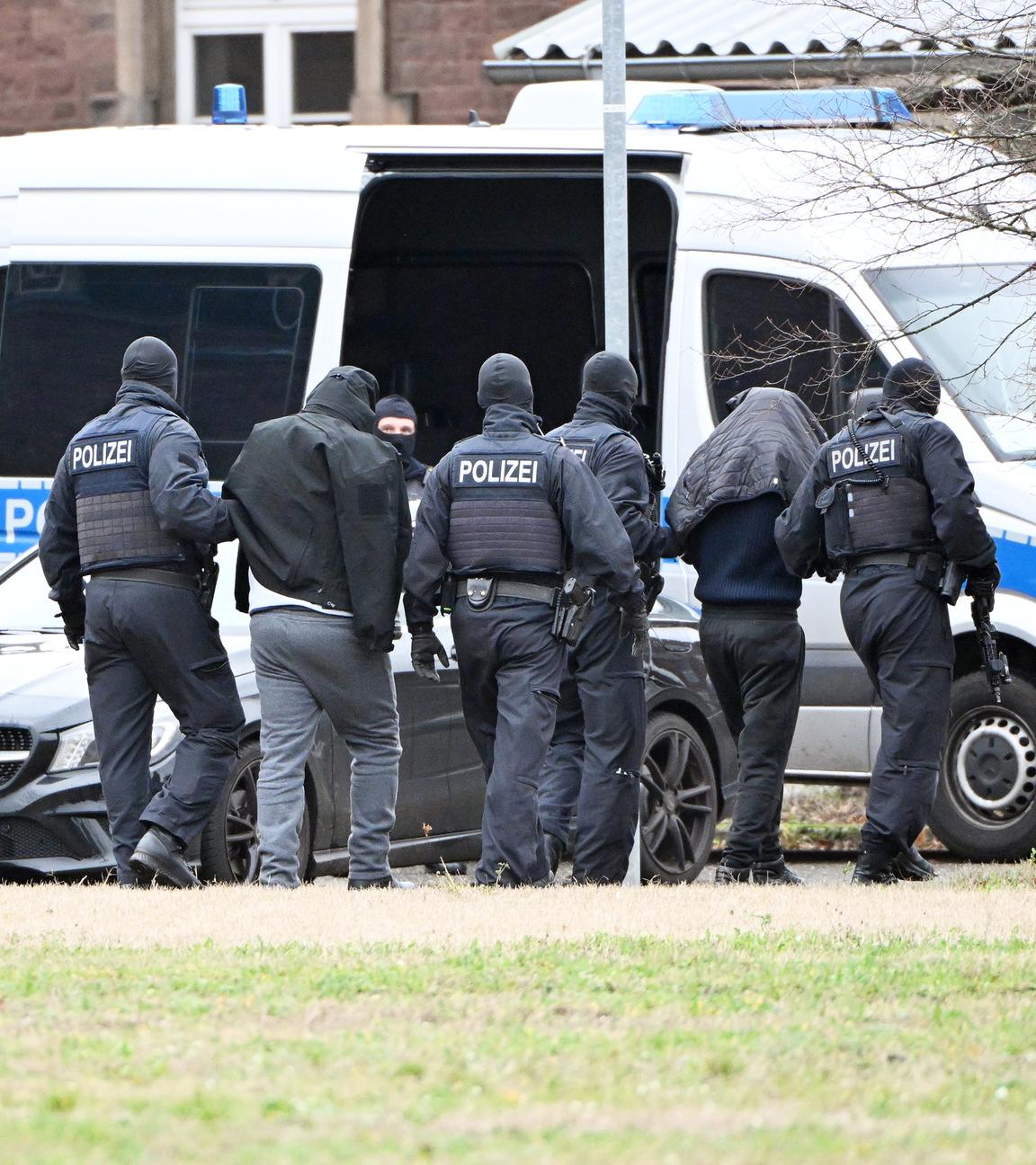 Baden-Württemberg, Karlsruhe: Zwei Personen werden von Polizisten bei einem Hubschrauberlandeplatz von einem Hubschrauber zu einem Auto geführt.