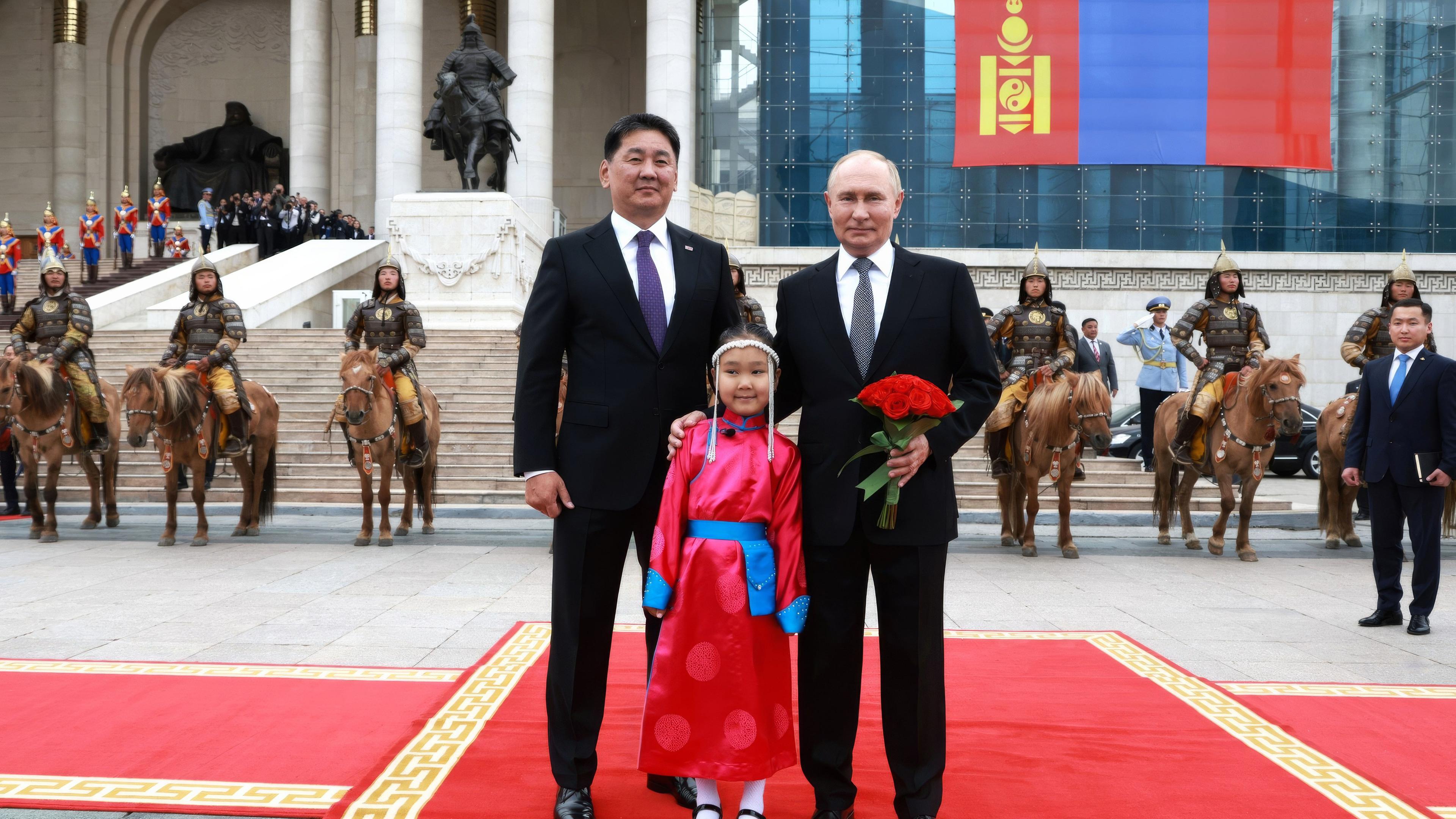 Archiv:  Der russische Präsident Wladimir Putin (r)posiert mit dem mongolischen Präsidenten Uchnaagiin Chürelsüch und einem jungen Blumenmädchen während der Ankunftszeremonie im Regierungspalast auf dem Sukhbaatar-Platz am 03.09.2024 in Ulan-Bator, Mongolei